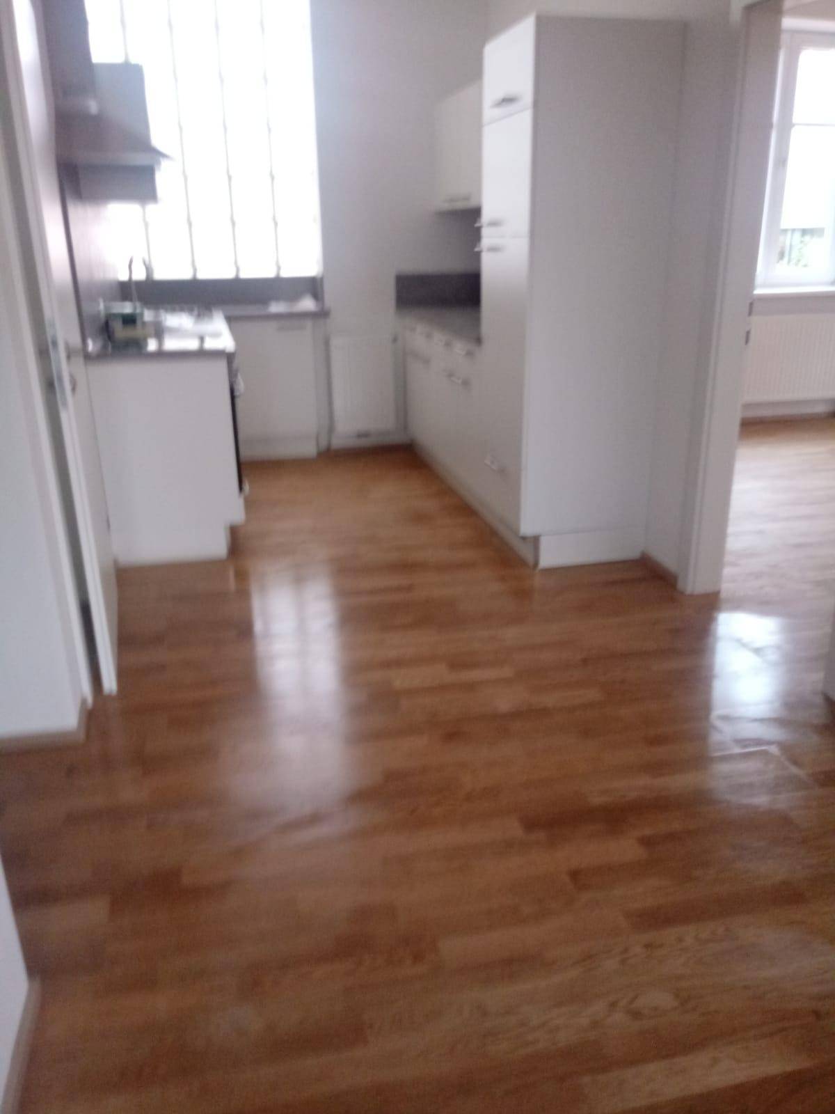Offener Wohnbereich mit Holzparkettboden, der zur Küche führt.