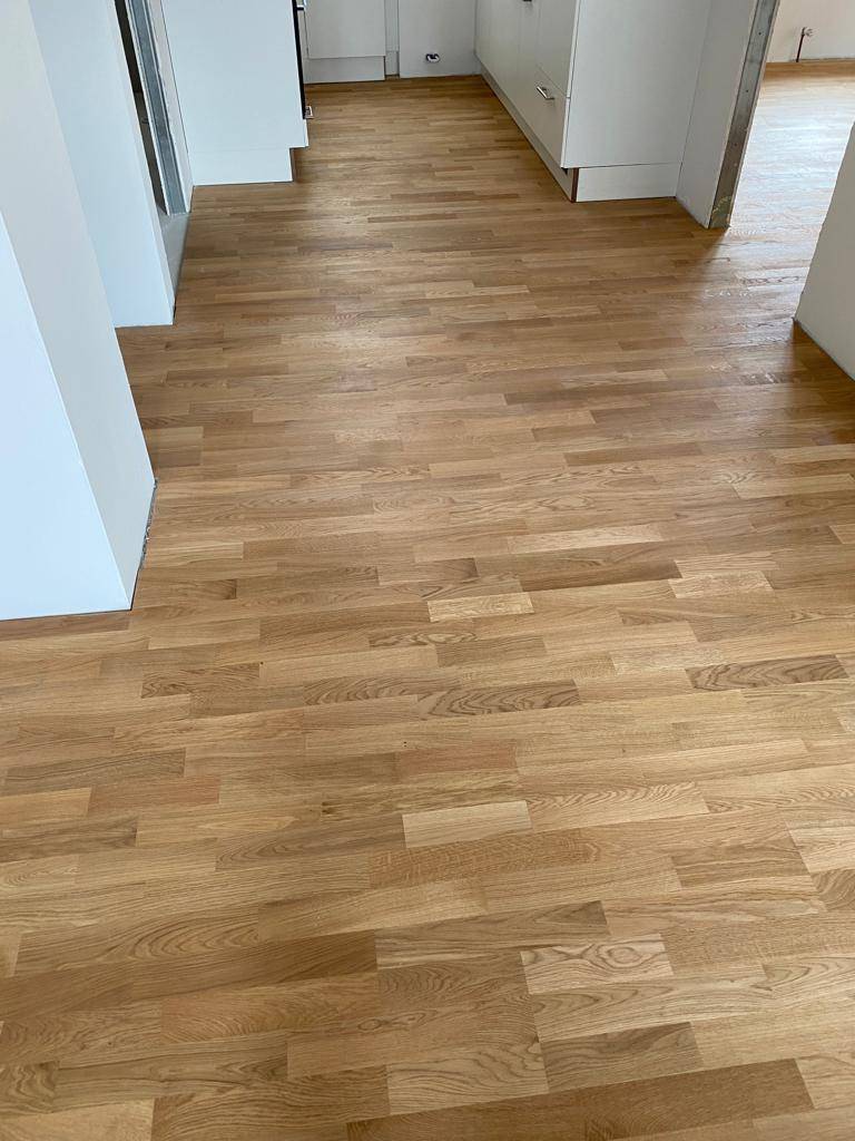 Heller Raum mit neu verlegtem Holzparkettboden und weißen Wänden.