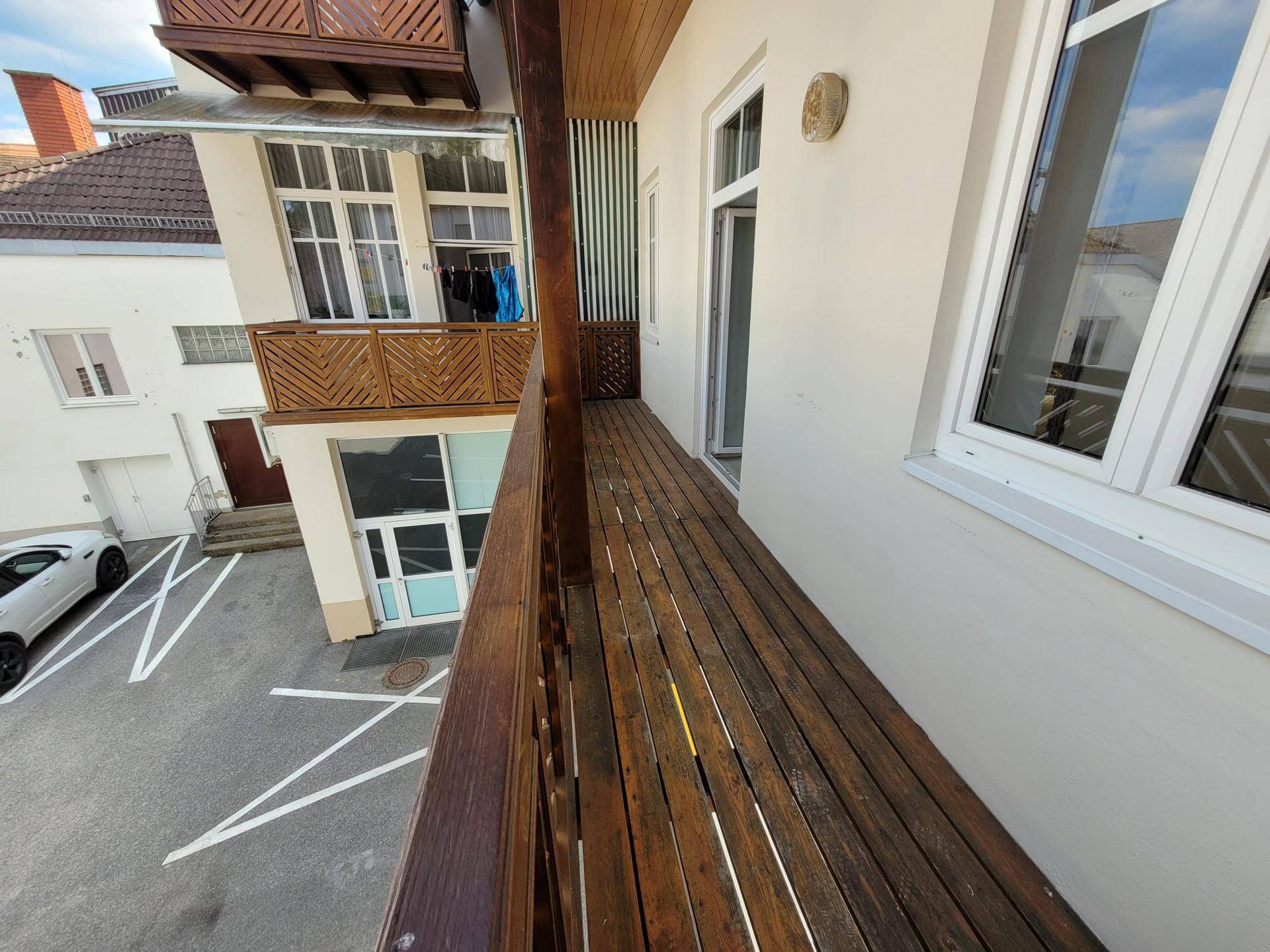Langer Holzbalkon mit Blick auf den Innenhof und die umliegenden Gebäude.