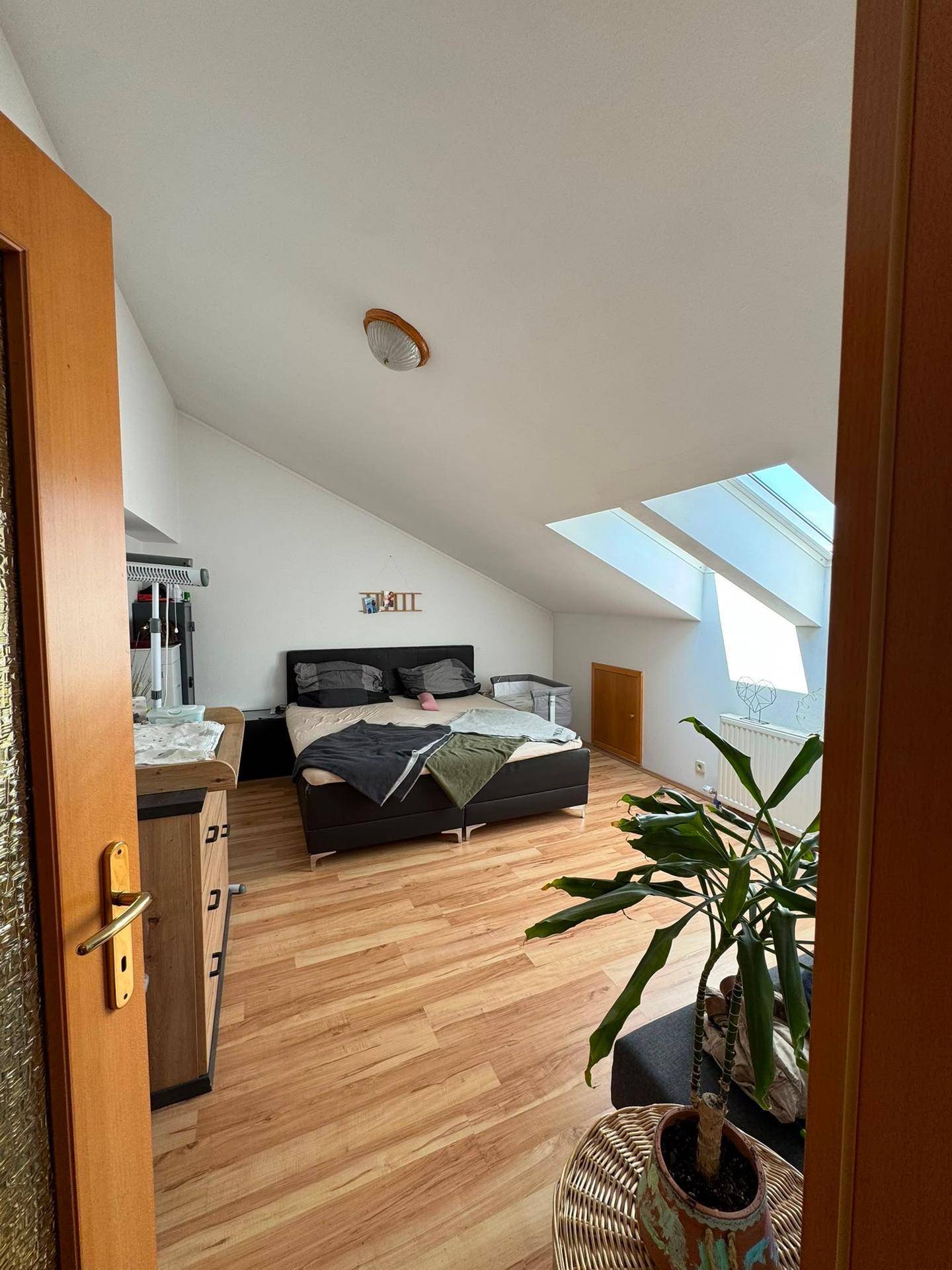 Gemütliches Schlafzimmer im Dachgeschoss mit Bett, Kommode und Dachfenstern für Helligkeit.