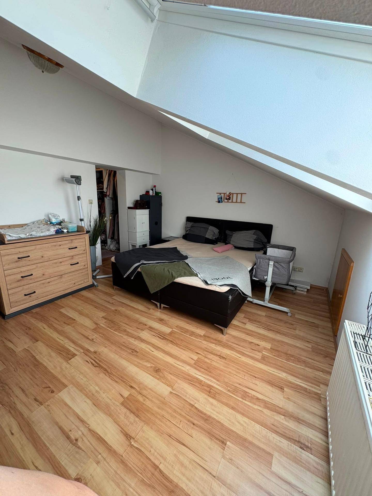 Geräumiges Schlafzimmer im Dachgeschoss mit Bett, Kommode und Dachfenstern für Helligkeit.