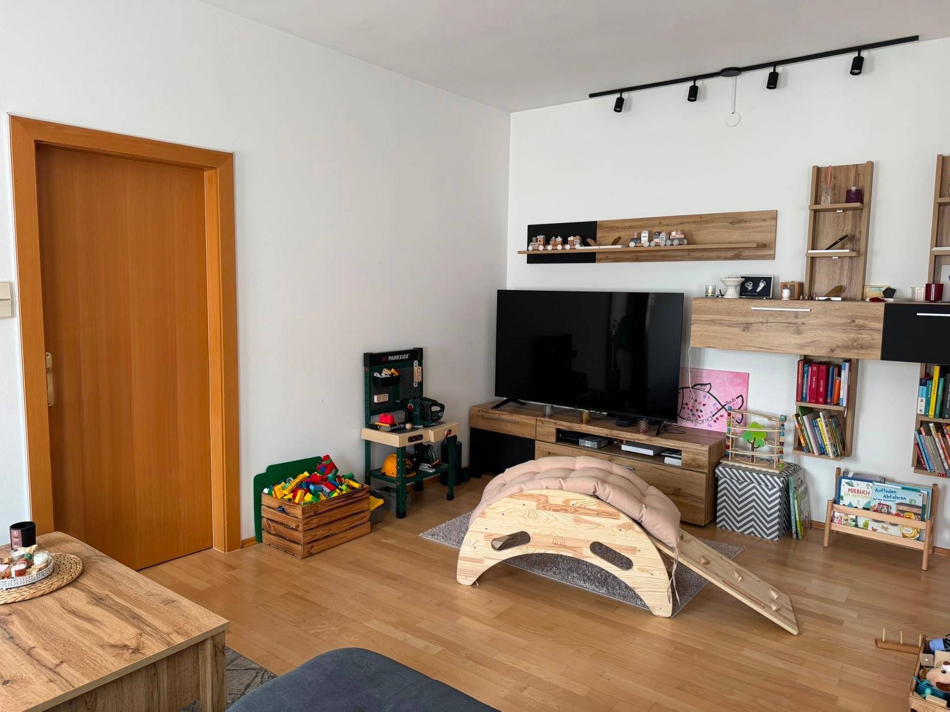 Wohnzimmer mit Fernseher, Unterhaltungsmöbeln und Kinderspielzeug, ideal für Familien.