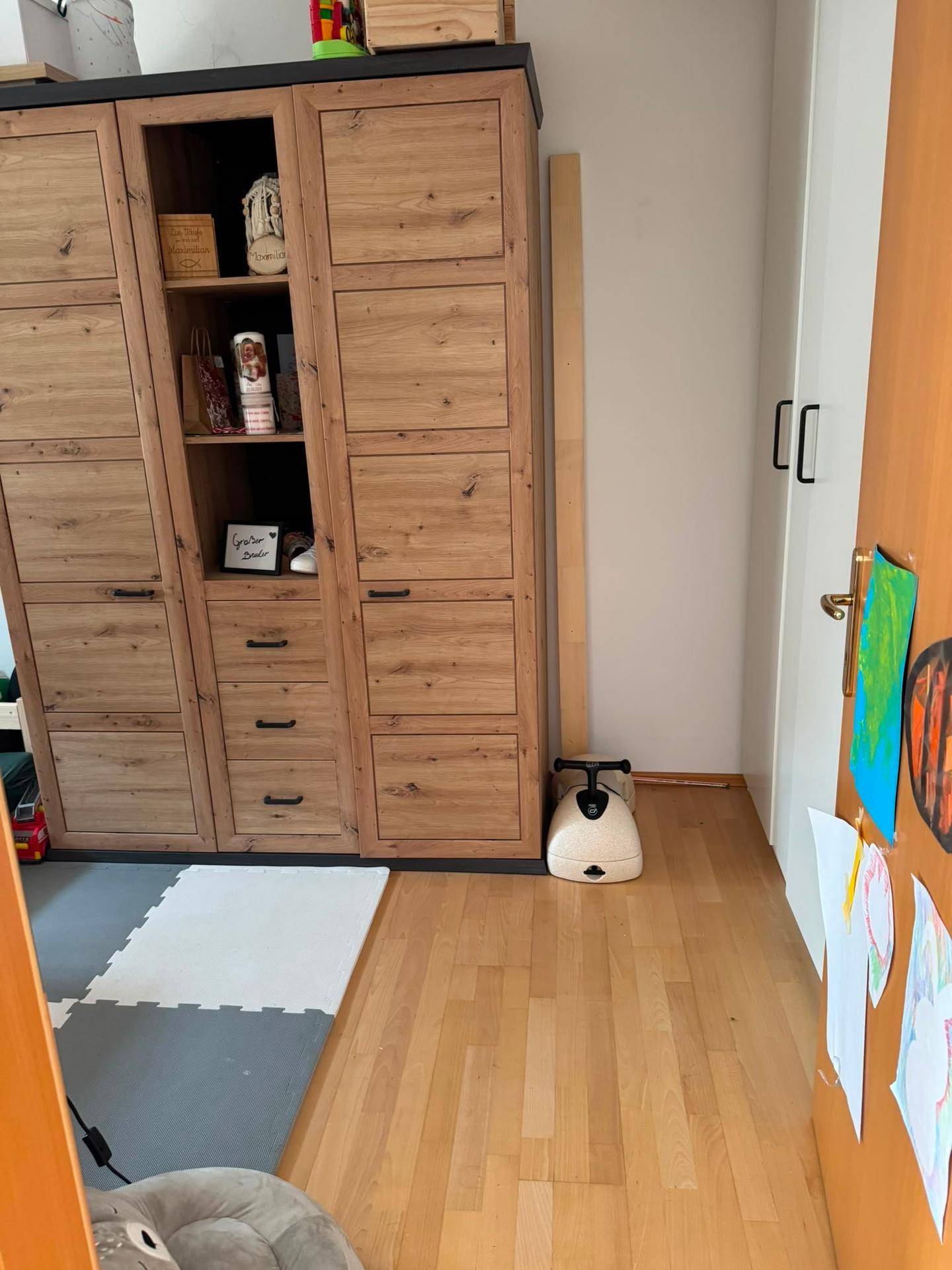 Innenraum mit großem Holzschrank und Spielmatte auf dem Boden, bietet Stauraum.