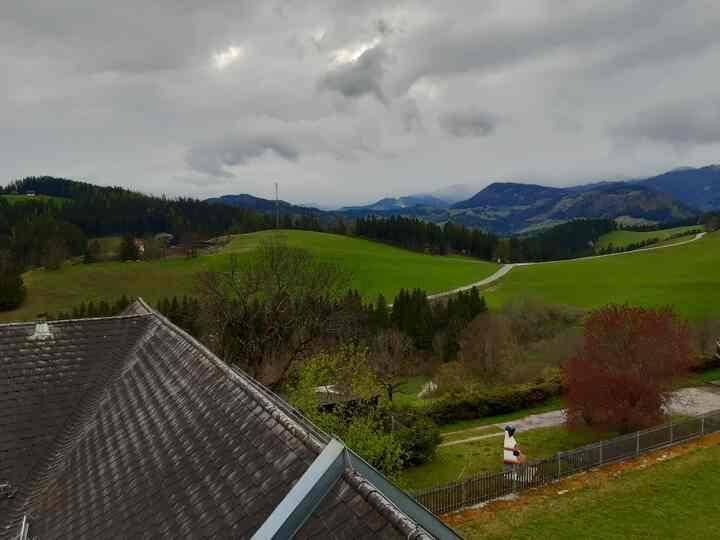 Weitläufiger Blick über grüne Hügel und Wälder unter bewölktem Himmel.