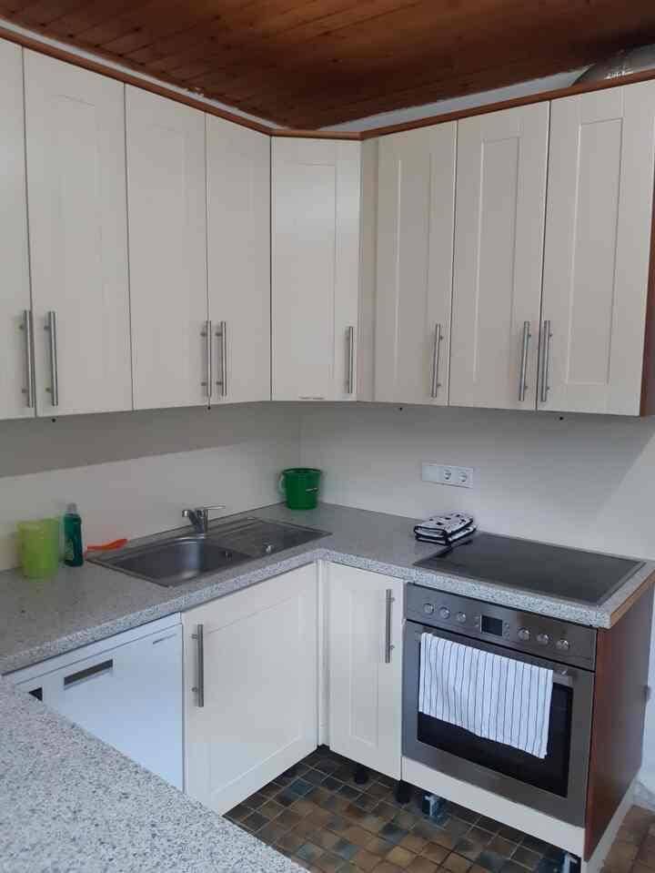 Funktionale Küche mit hellen Schränken, Spüle, Herd und integriertem Backofen.