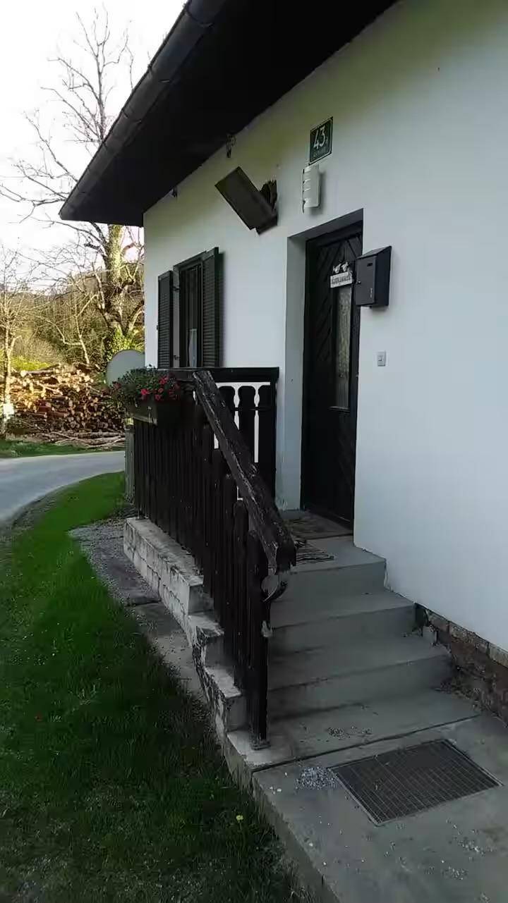 Eingangsbereich eines Hauses mit Holzgeländer und Treppe zur Haustür.