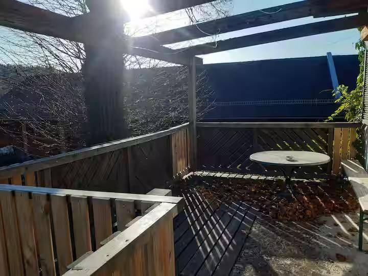 Sonnige Holzterrasse mit Sitzgelegenheit und Blick auf die Umgebung.