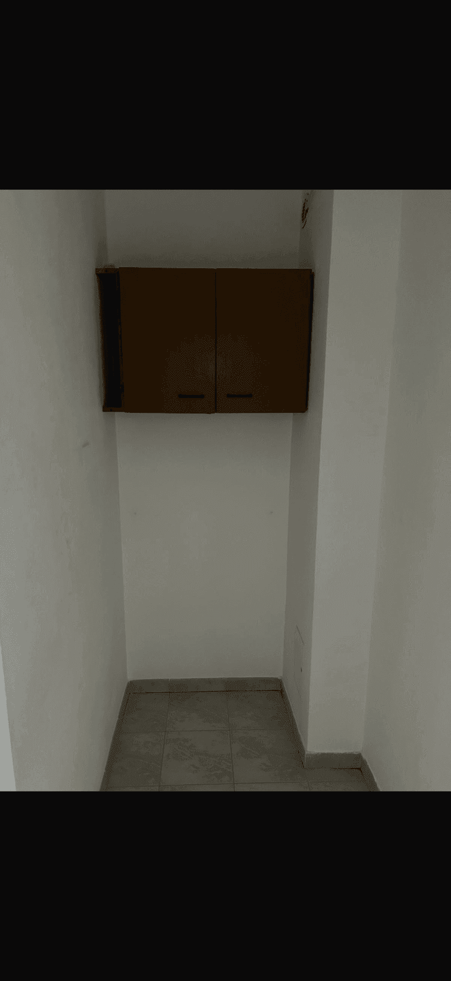 Kleiner Abstellraum mit Fliesenboden und einem Hängeschrank für zusätzlichen Stauraum.