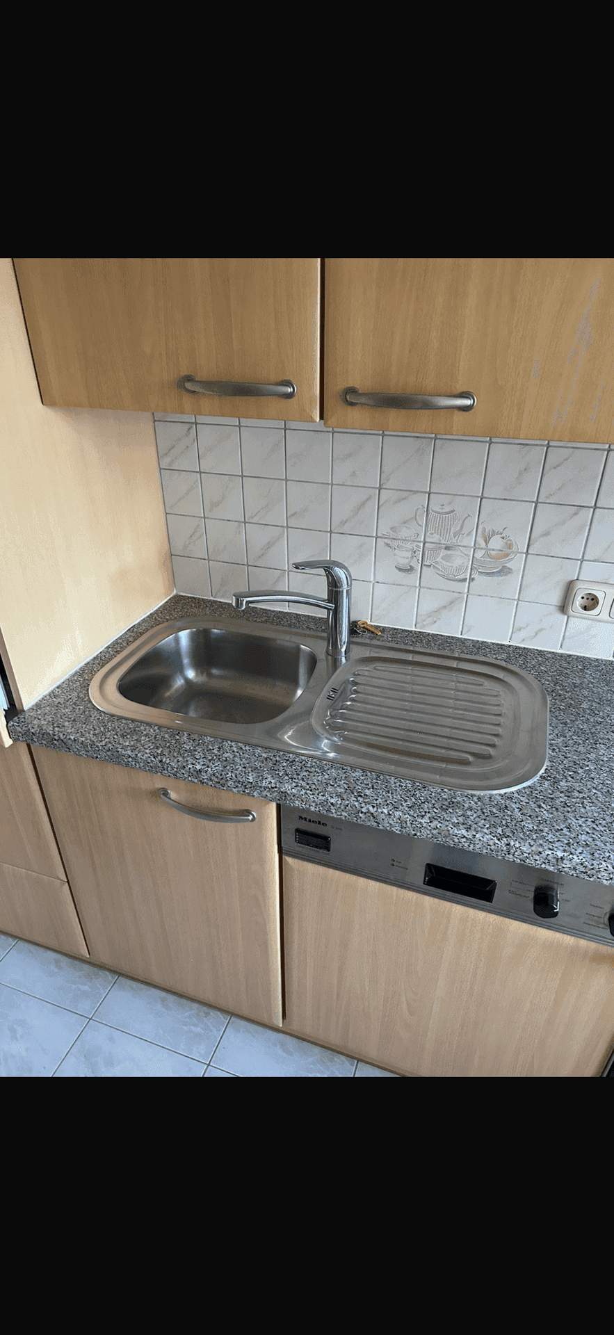 Küchenzeile mit Holzschränken, Granit-Arbeitsplatte, Spüle und integriertem Geschirrspüler.