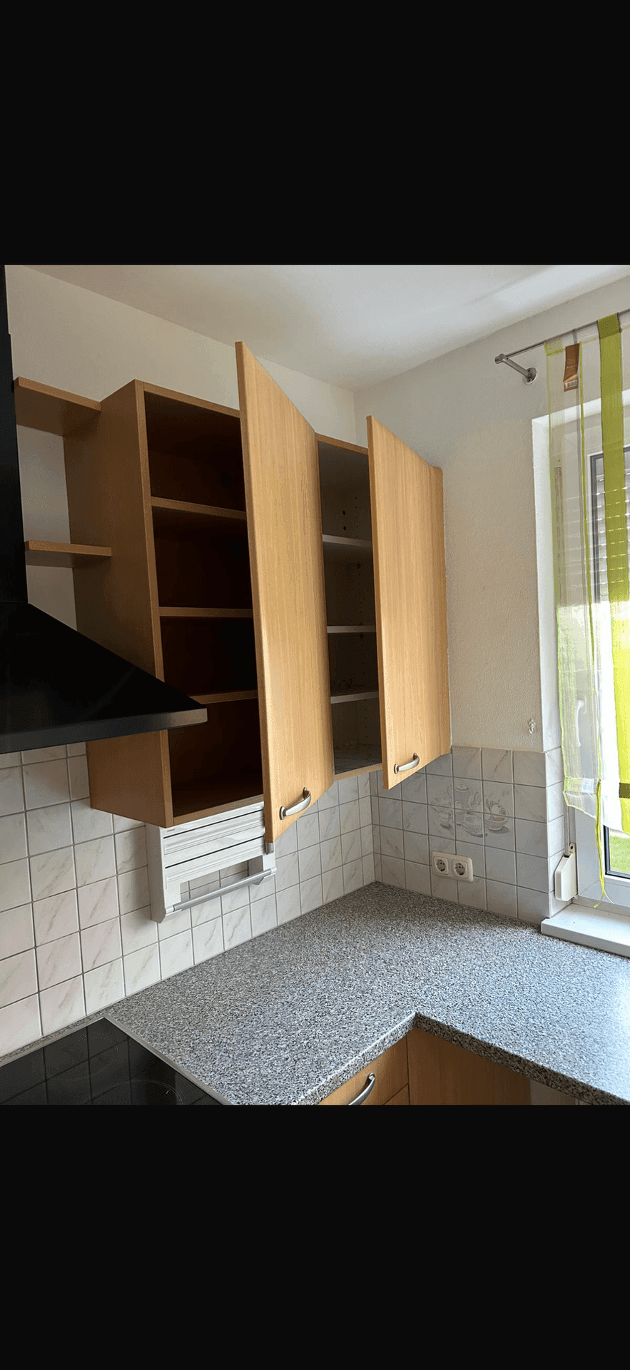 Küchenbereich mit Oberschränken aus Holz, Granit-Arbeitsplatte, Induktionskochfeld und Dunstabzugshaube.