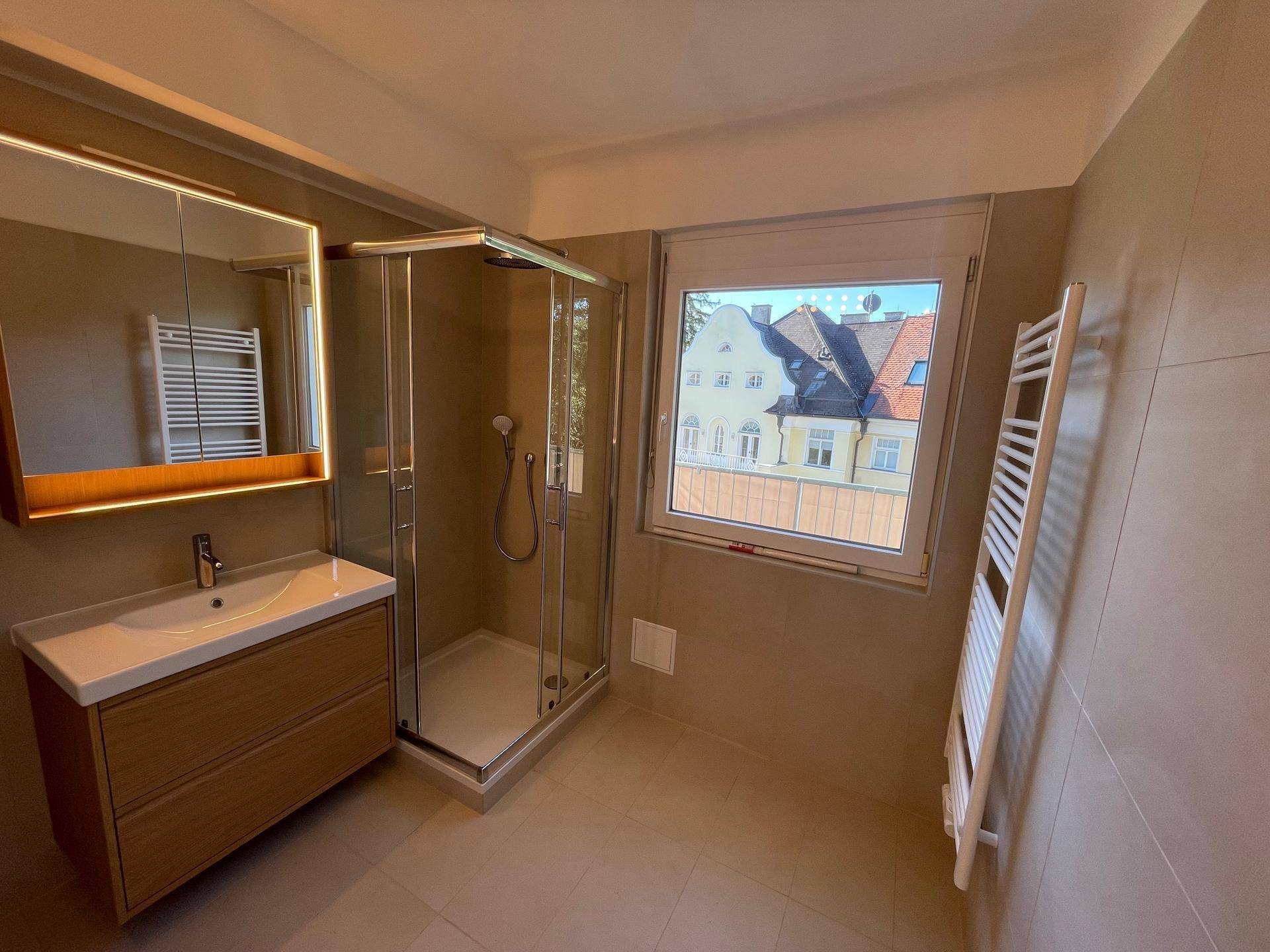 Modernes Badezimmer mit Dusche, Einzelwaschbecken, Spiegelschrank und Handtuchheizkörper.