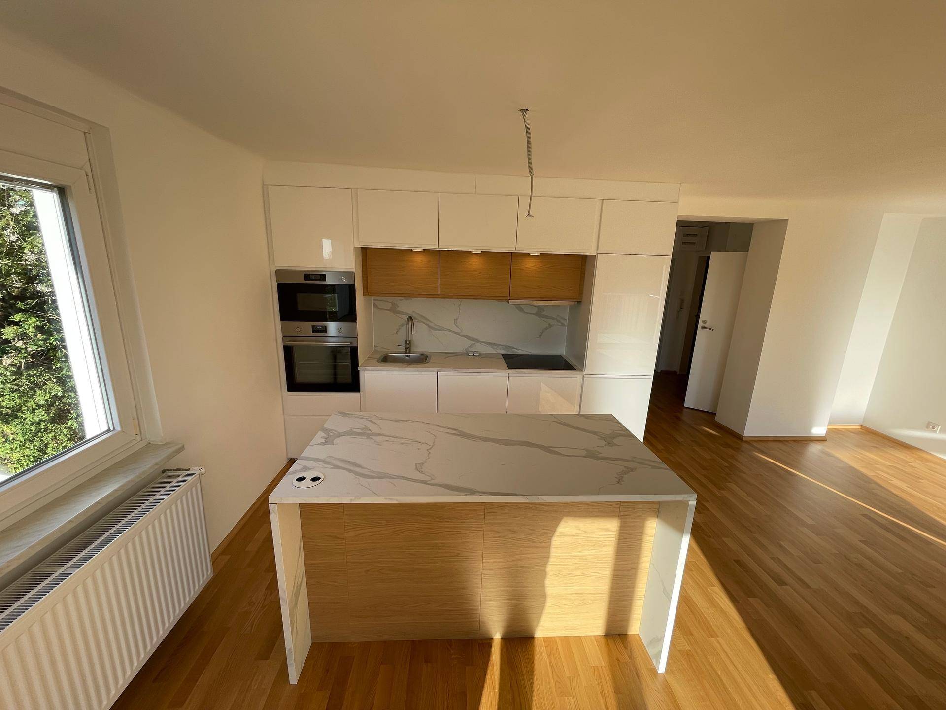 Moderne Einbauküche mit weißen Hochglanzfronten, Kochinsel und integrierten Geräten.