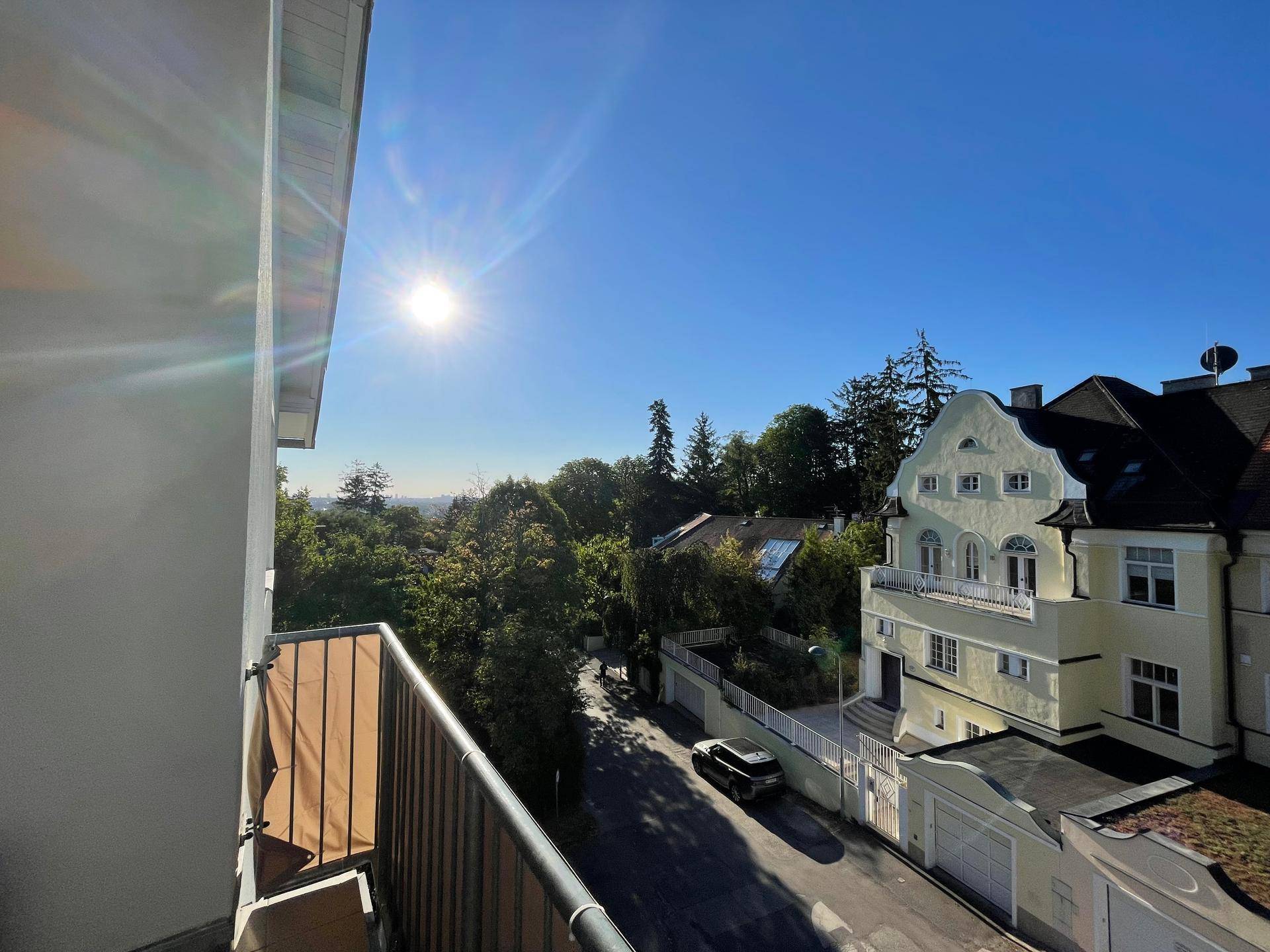 Sonniger Ausblick vom Balkon auf eine ruhige Straße und umliegende Villen.