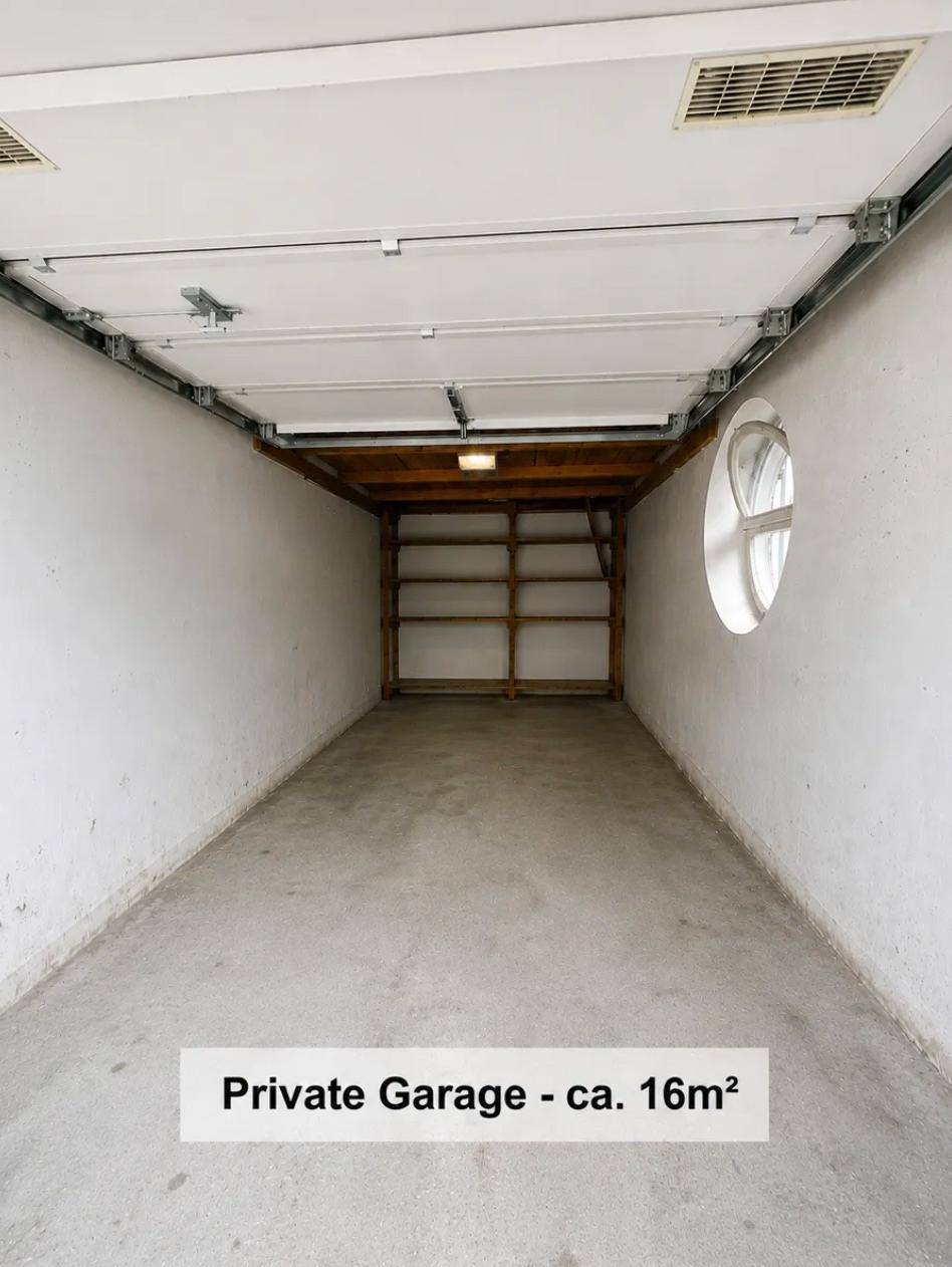 Leere private Garage mit Betonboden und einem runden Fenster, ca. 16m² groß.