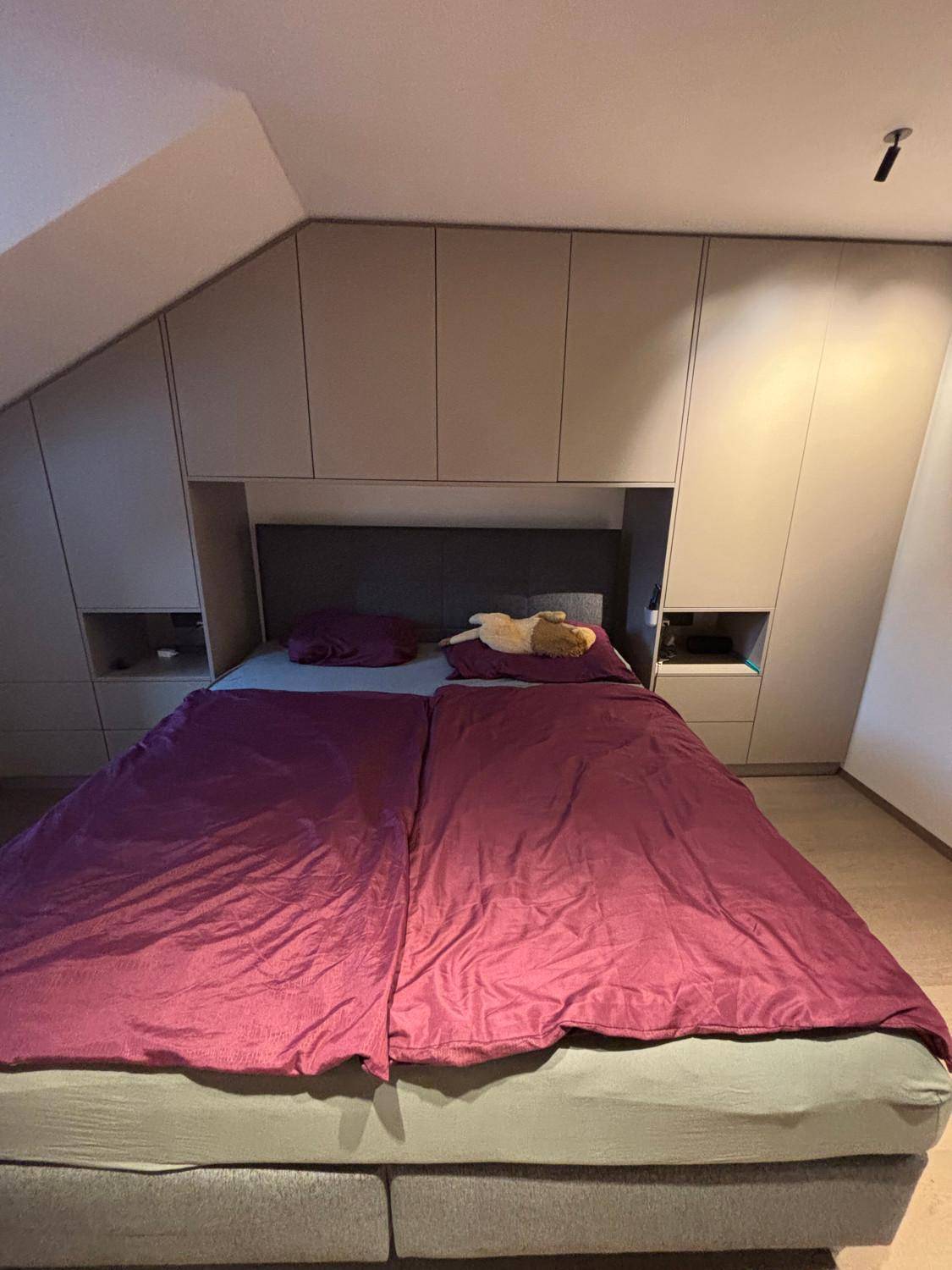 Schlafzimmer mit Doppelbett und maßgefertigten Einbauschränken unter der Dachschräge.