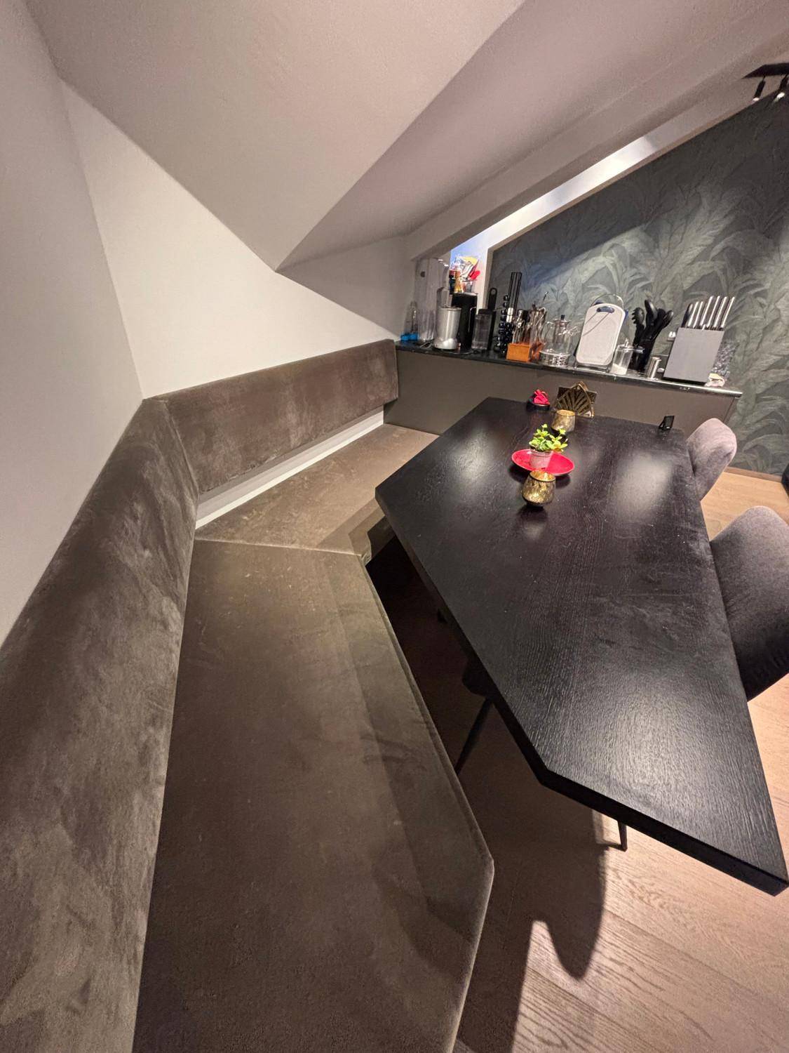 Gemütlicher Essbereich mit eingebauter Sitzbank und dunklem Holztisch unter der Dachschräge.