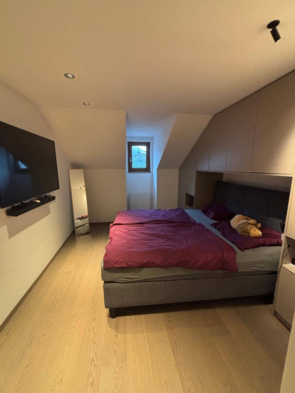 Schlafzimmer mit Doppelbett, Einbauschränken und Dachschrägen, gut beleuchtet.