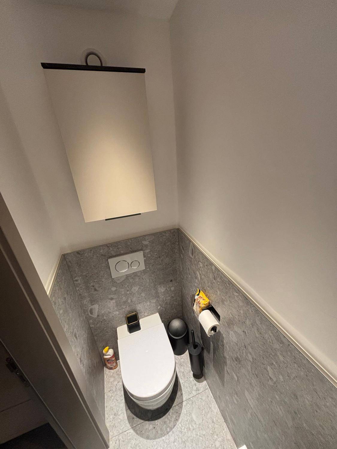 Kleines Gäste-WC mit wandhängendem WC und modernen grauen Fliesen.