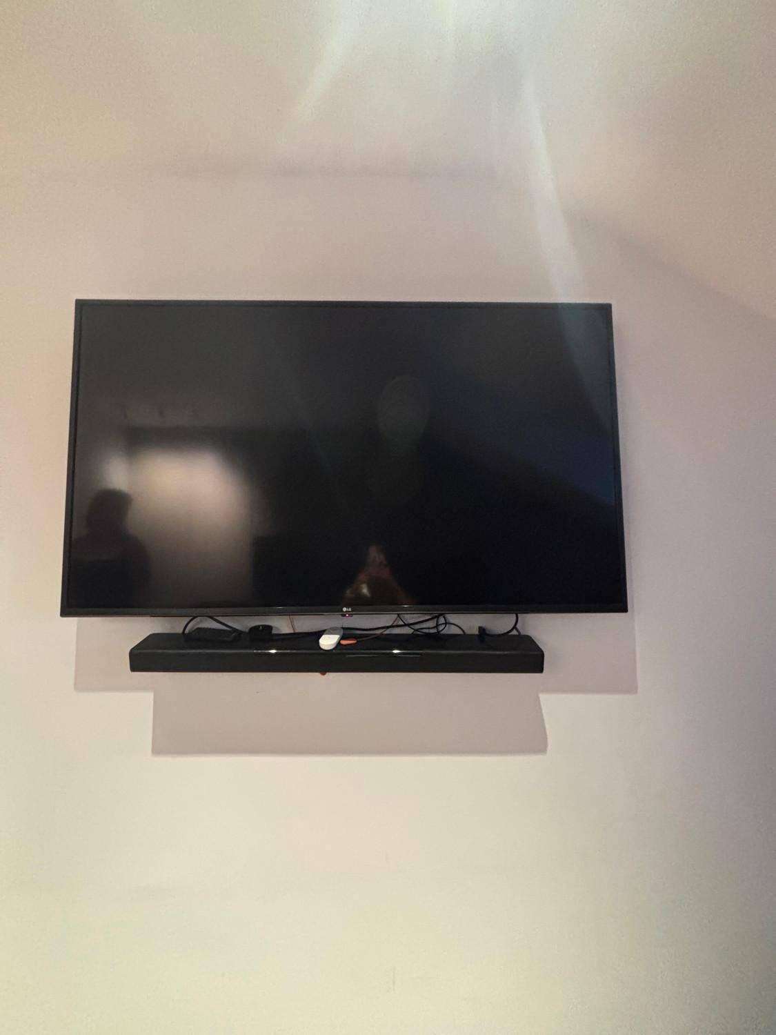 Wandmontierter Fernseher mit Soundbar in einem modernen Wohnbereich.