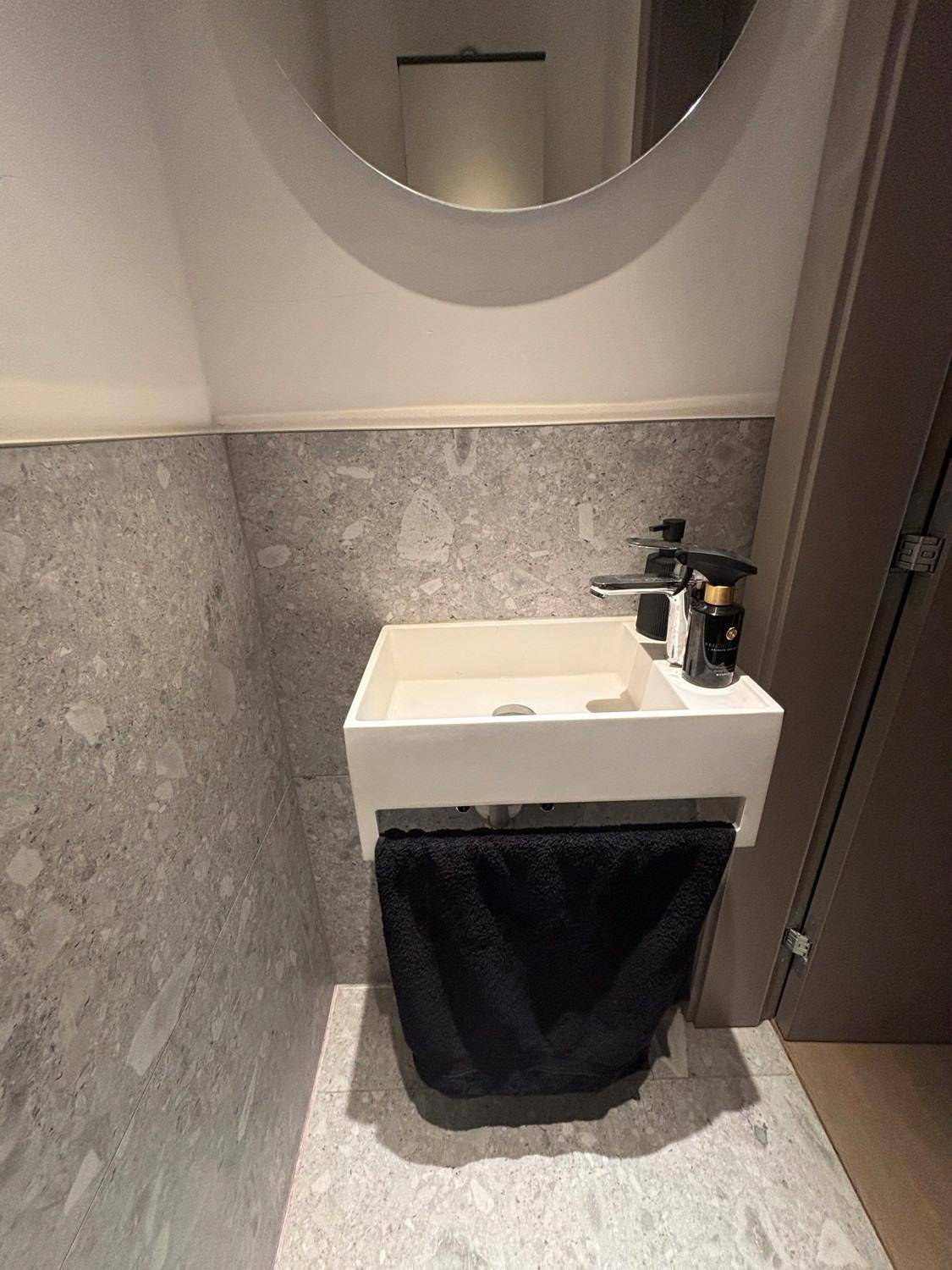 Modernes Gäste-WC mit minimalistischem Waschbecken und grauen Fliesen.