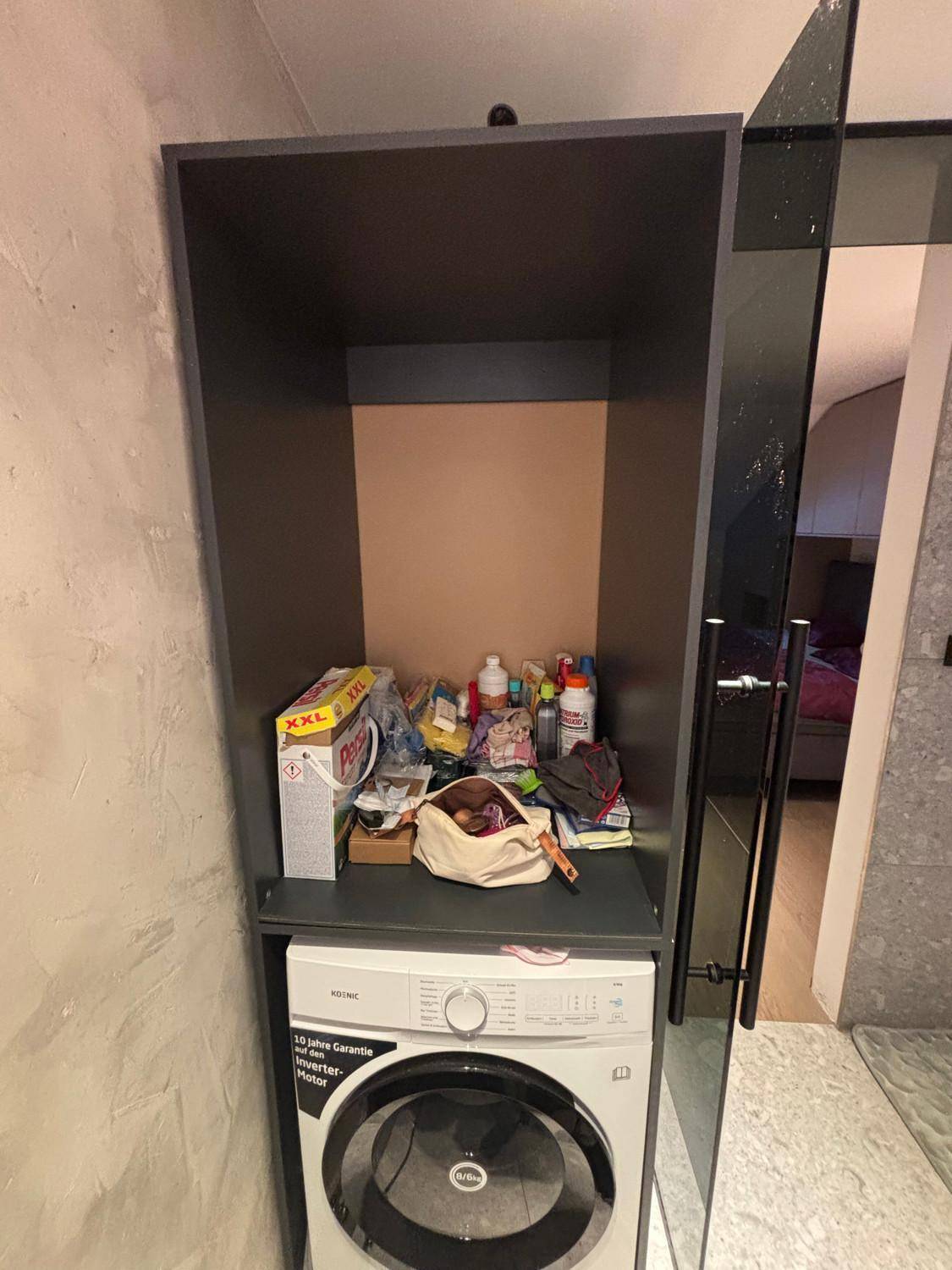 Praktischer Wäscheschrank mit Waschmaschine und Stauraum für Reinigungsutensilien.