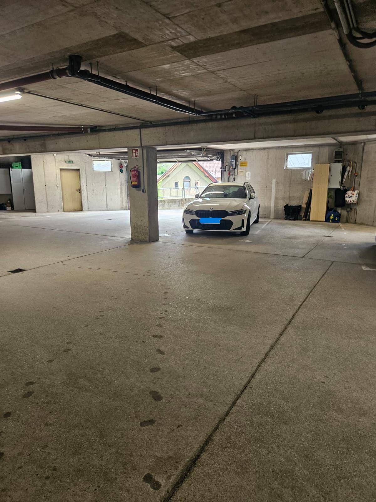 Tiefgarage mit Betonboden und einem geparkten Fahrzeug, gut beleuchtet.