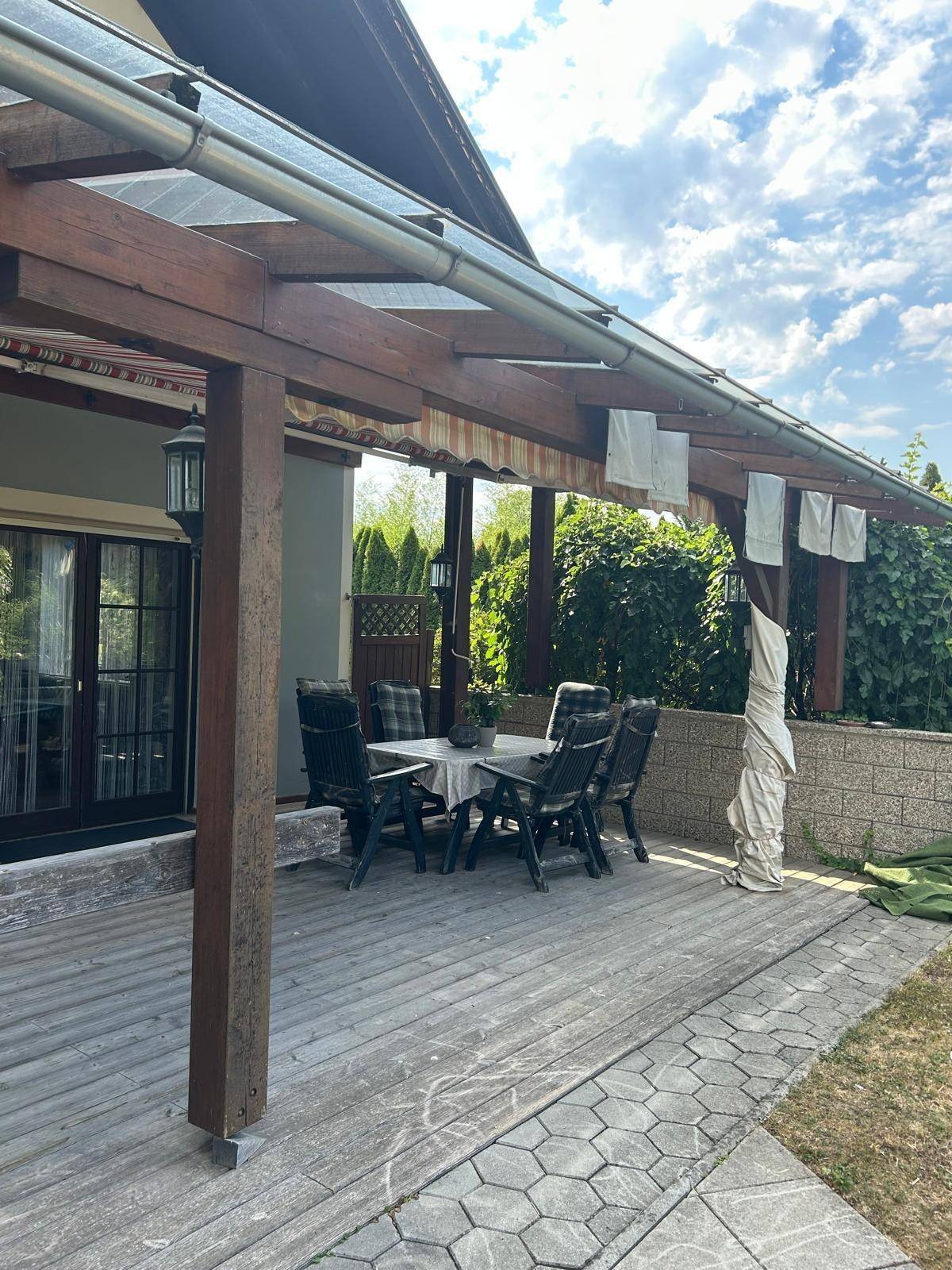 Überdachte Terrasse mit Holzboden und Gartenmöbeln, ideal für entspannte Stunden im Freien.