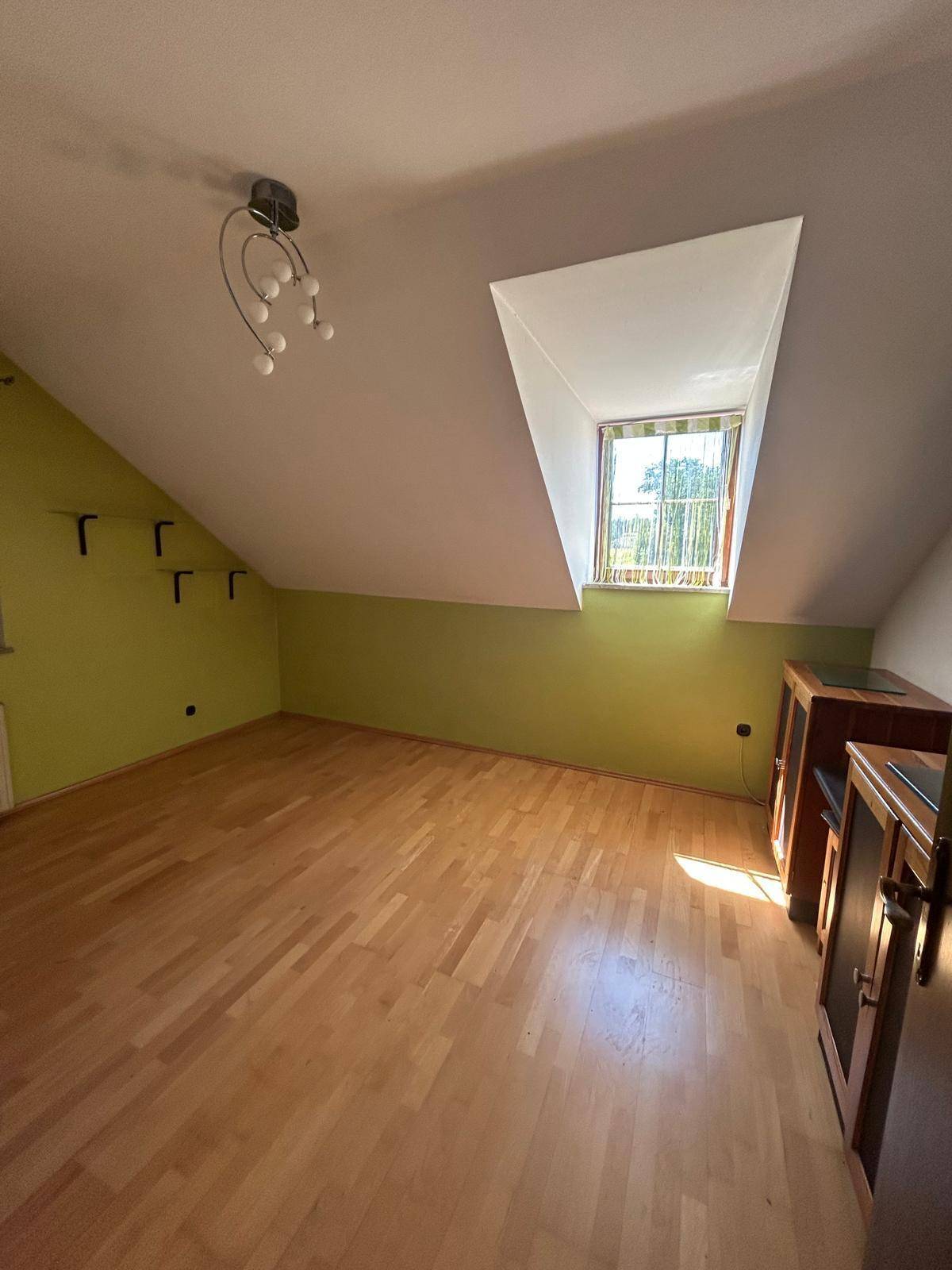 Schlafzimmer mit Dachschräge, Dachfenster und Laminatboden, hell und freundlich.