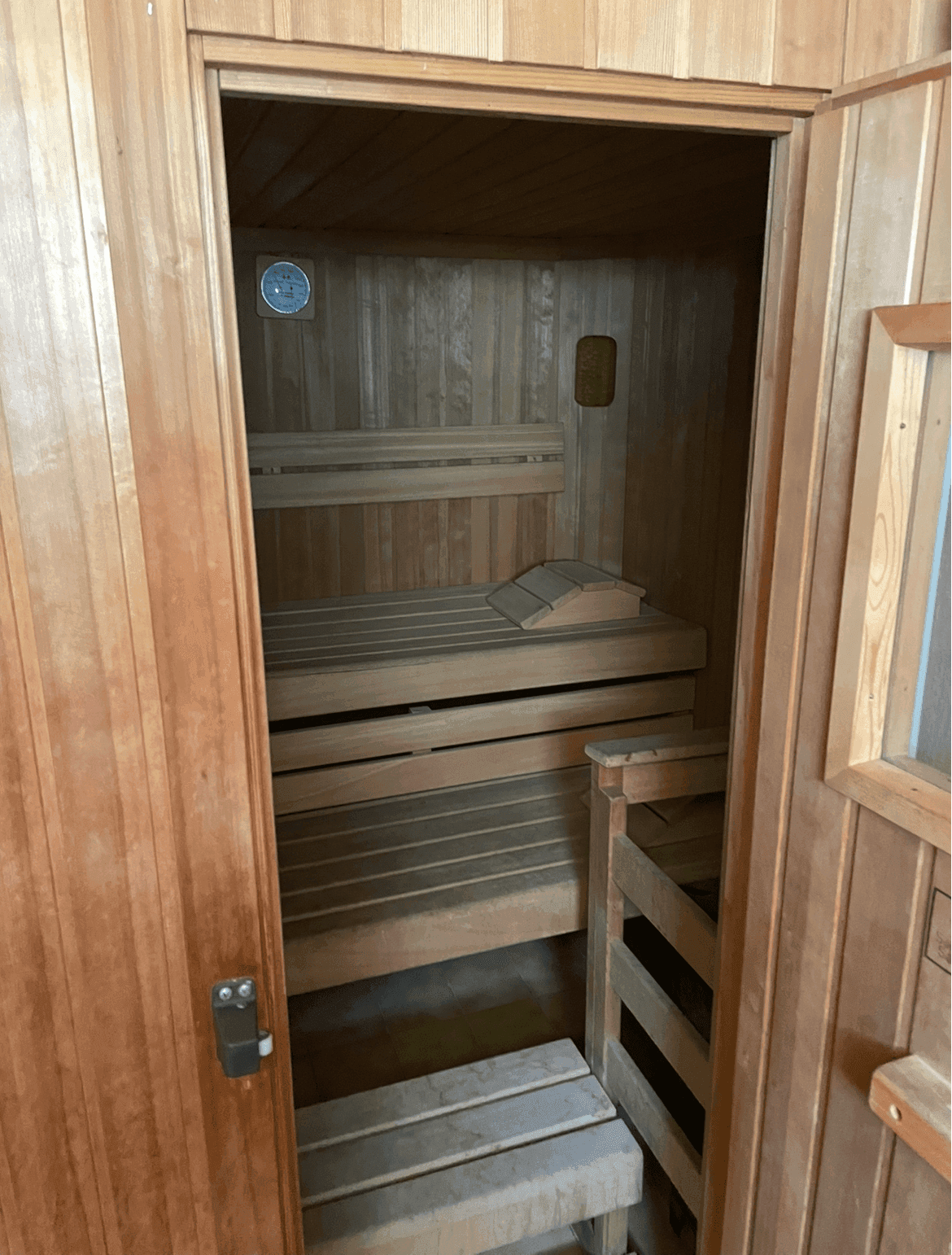 Gemütliche Holzsauna mit mehreren Bänken und integriertem Thermometer für entspannende Momente.