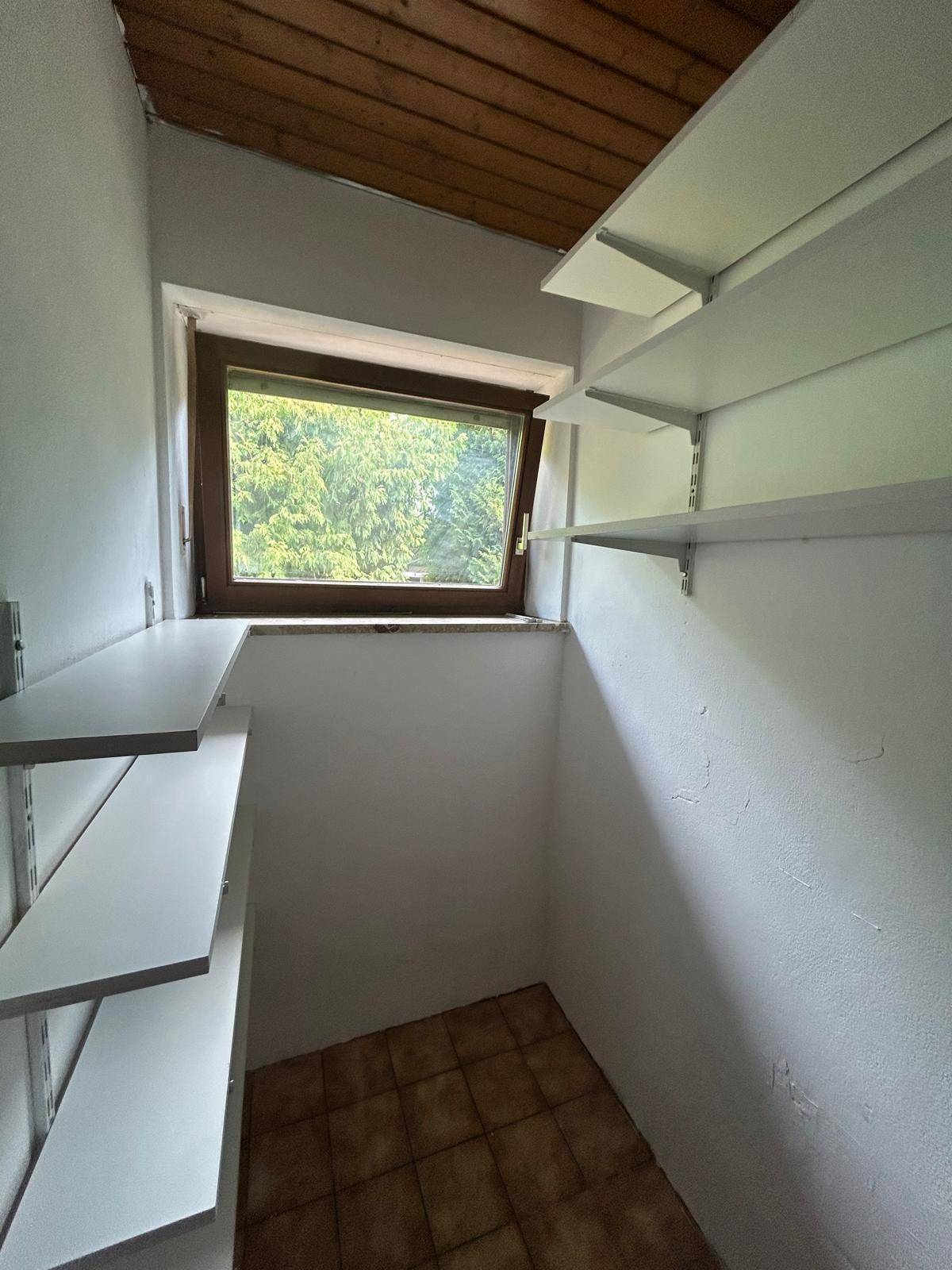 Kleiner Abstellraum mit Fenster und Regalen, perfekt für Vorräte oder Haushaltsartikel.