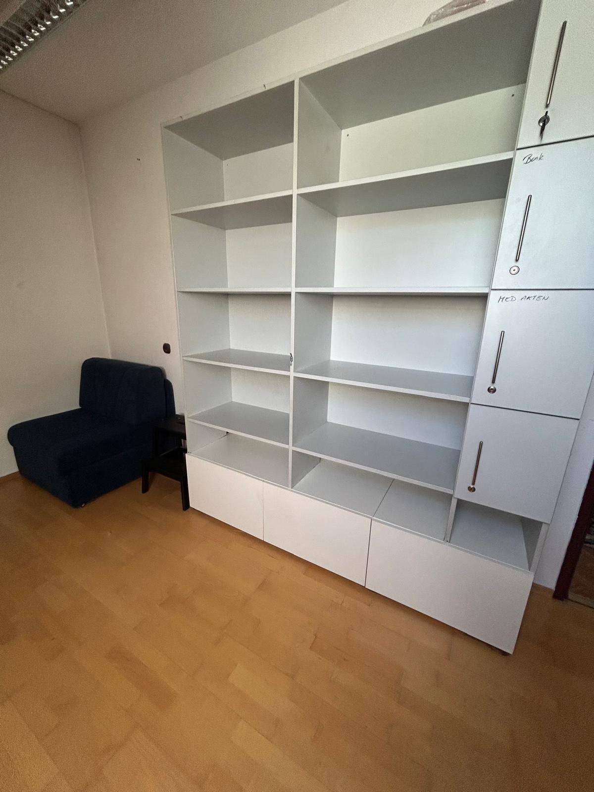 Zimmer mit großem weißen Regalsystem und einem Sessel, ideal als Arbeits- oder Gästezimmer.