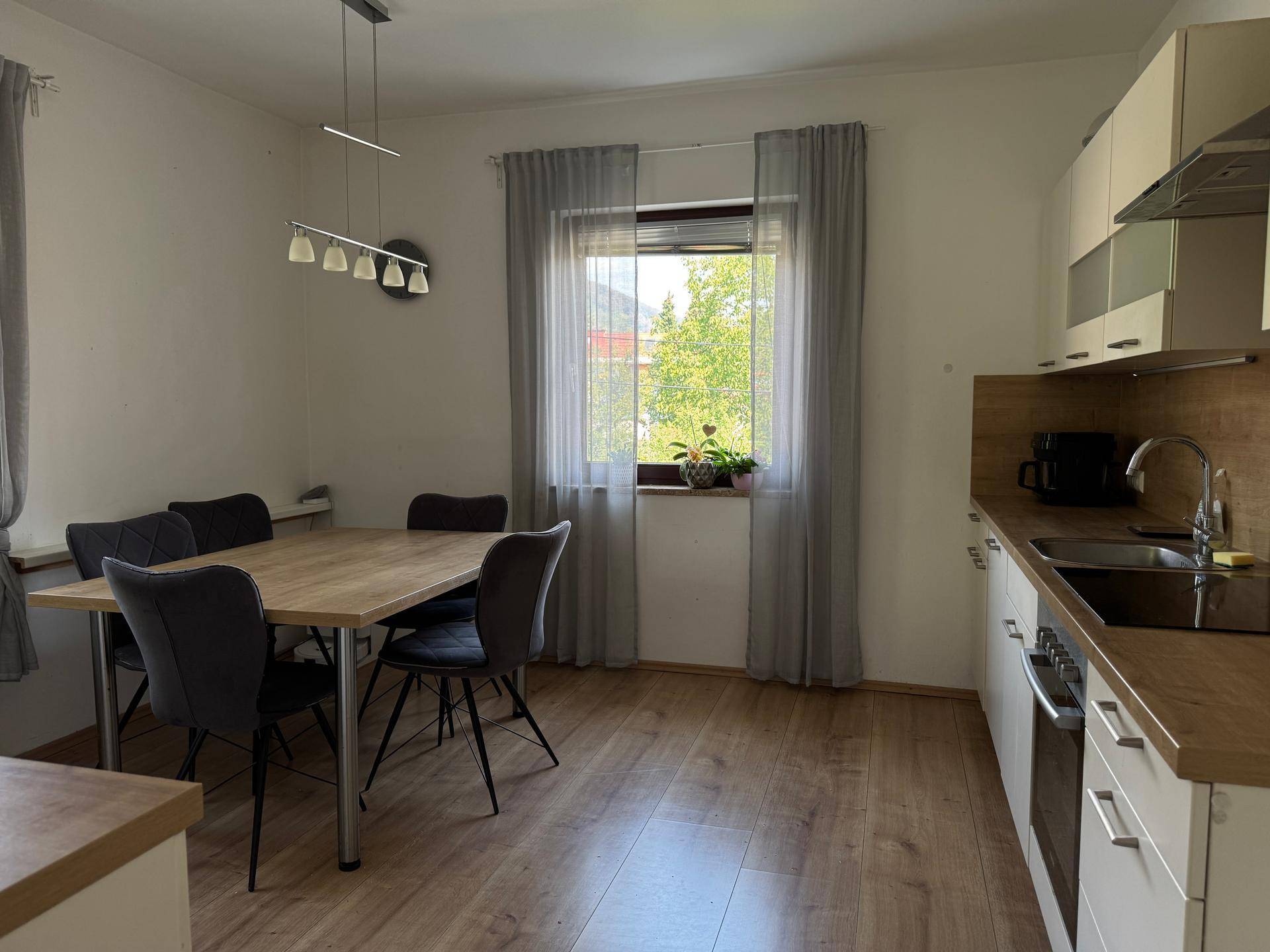 Moderne Wohnküche mit Esstisch, hellen Schränken und Fenster, ideal für gemeinsame Mahlzeiten.