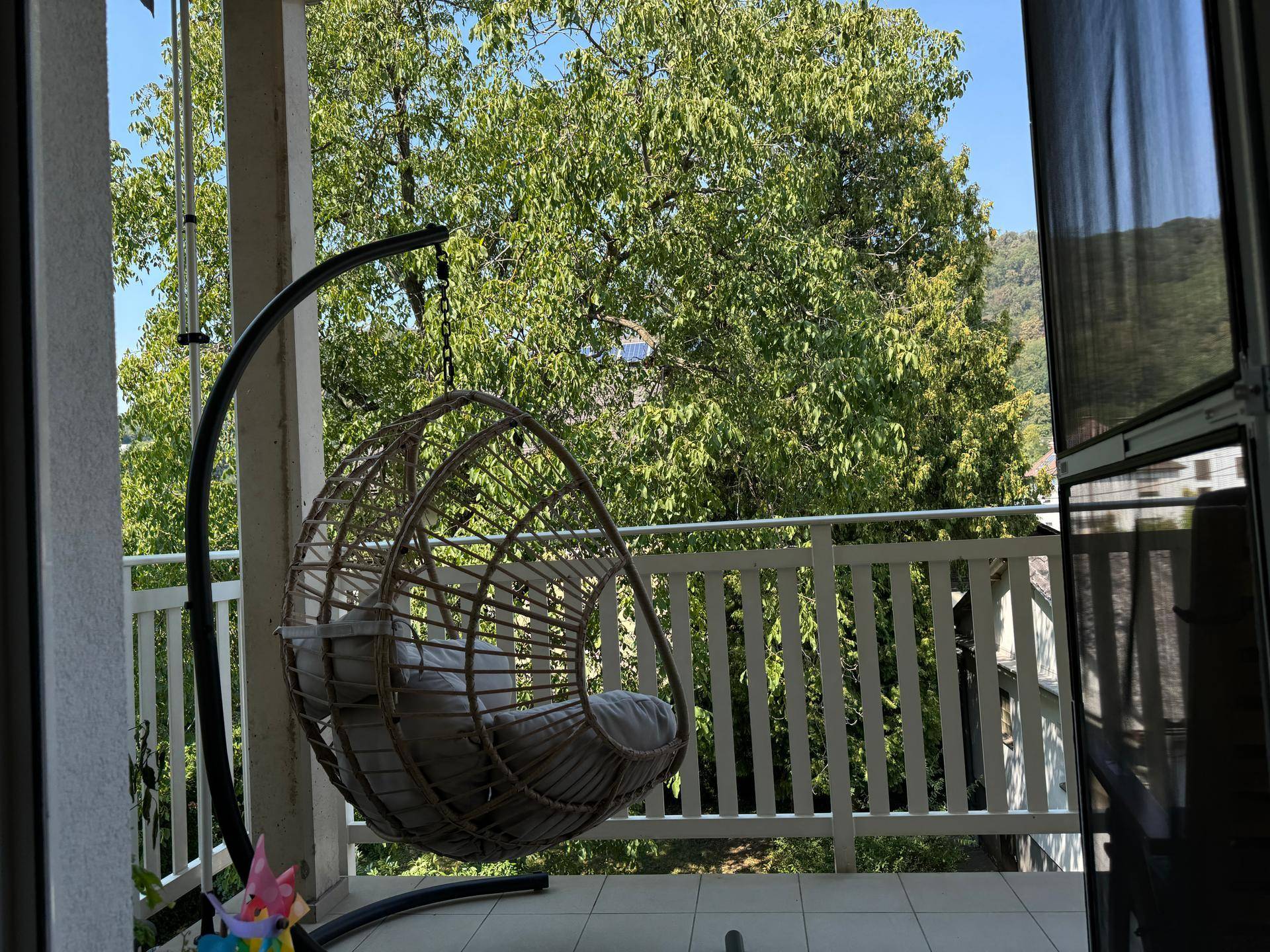 Heller Balkon mit gemütlichem Hängesessel und Blick ins Grüne, perfekt für sonnige Tage.