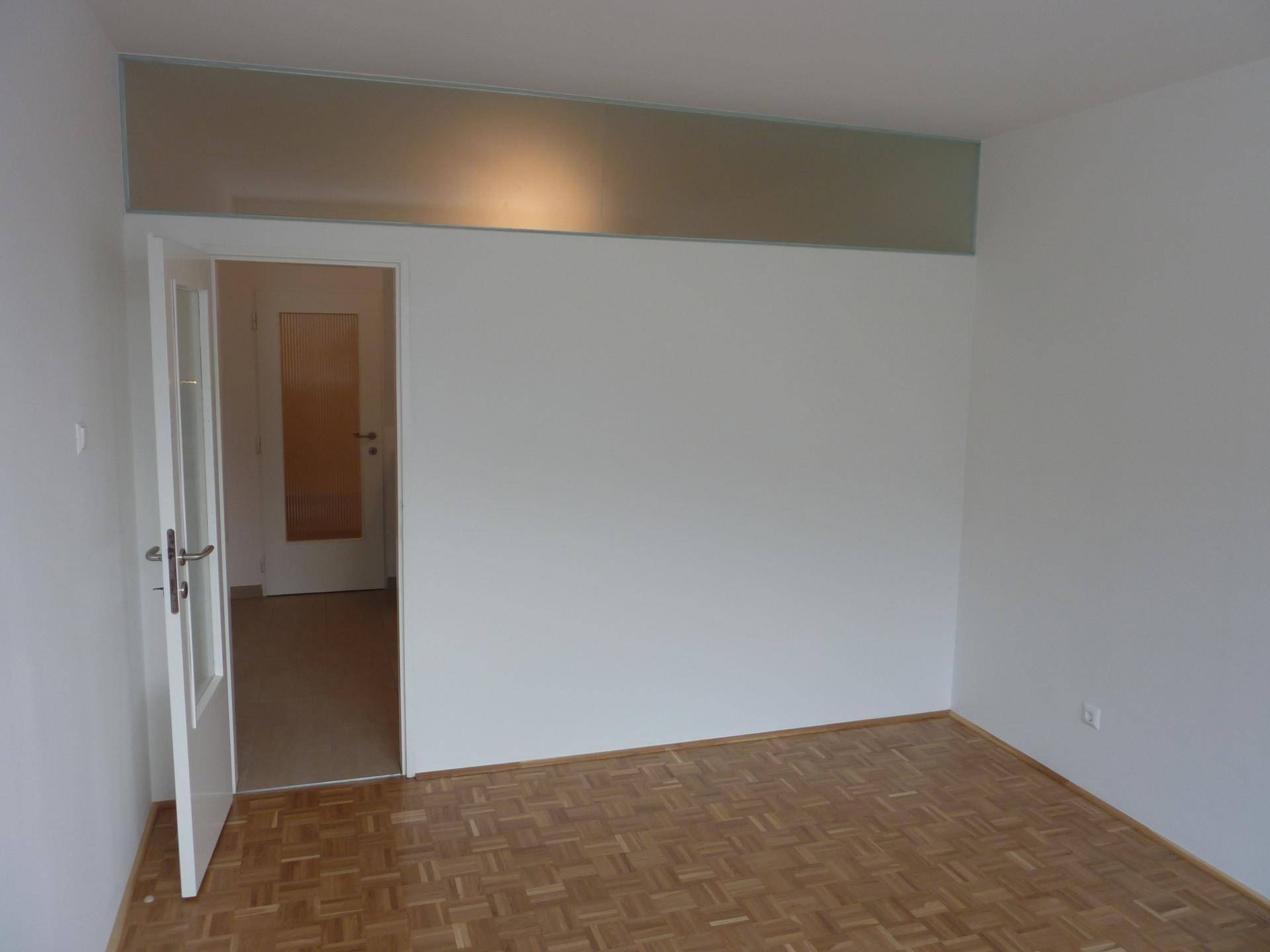 Geräumiger Raum mit Parkettboden und weißen Wänden, bereit zur individuellen Gestaltung.