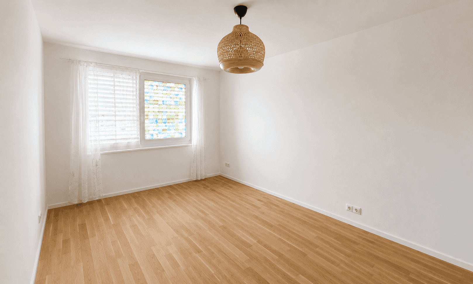 Ruhiges Schlafzimmer mit hellem Parkettboden und einem Fenster mit Jalousien.