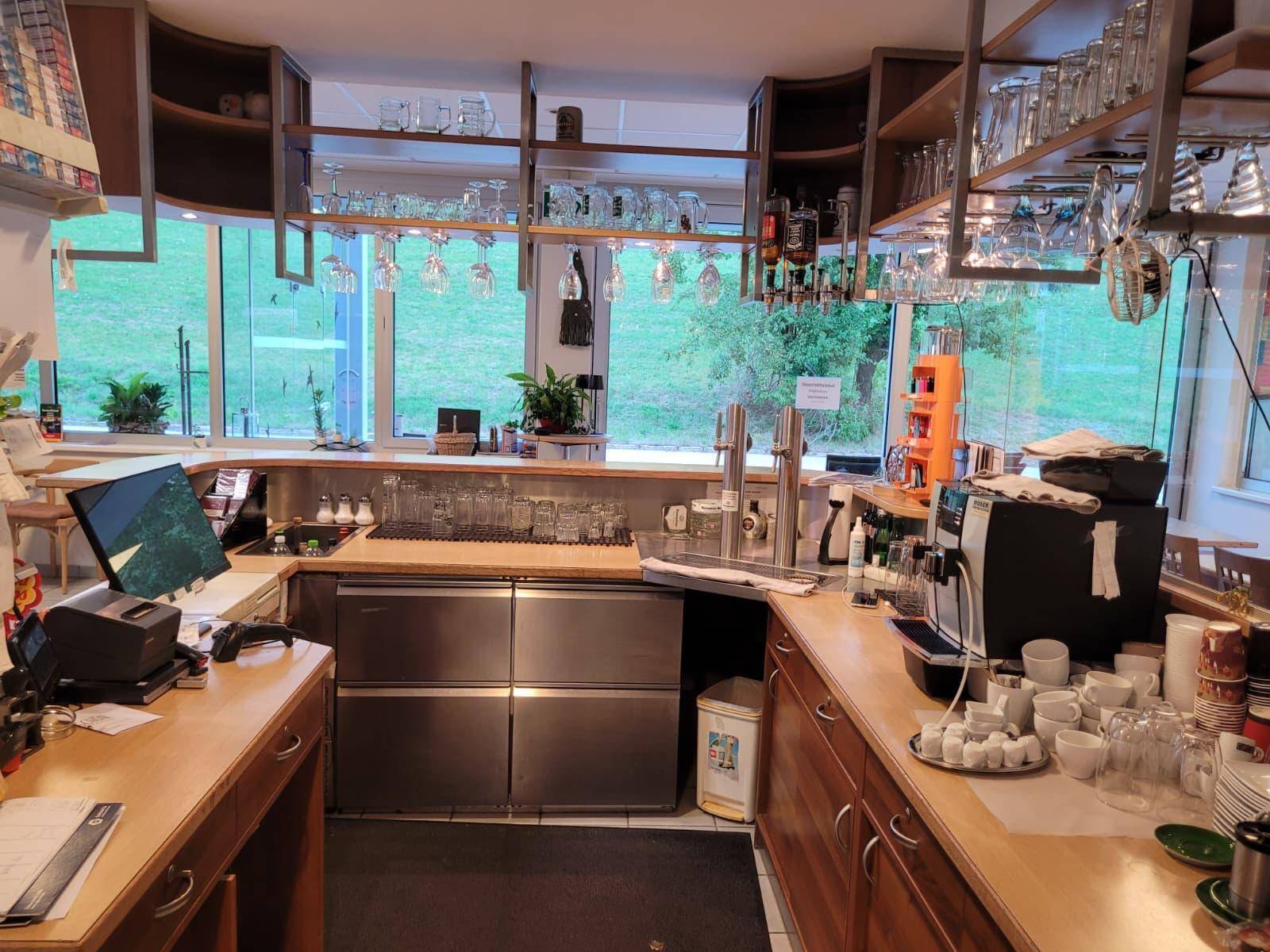 Detailansicht des Barbereichs mit Kaffeemaschinen, Gläsern und einem schönen Blick ins Grüne.