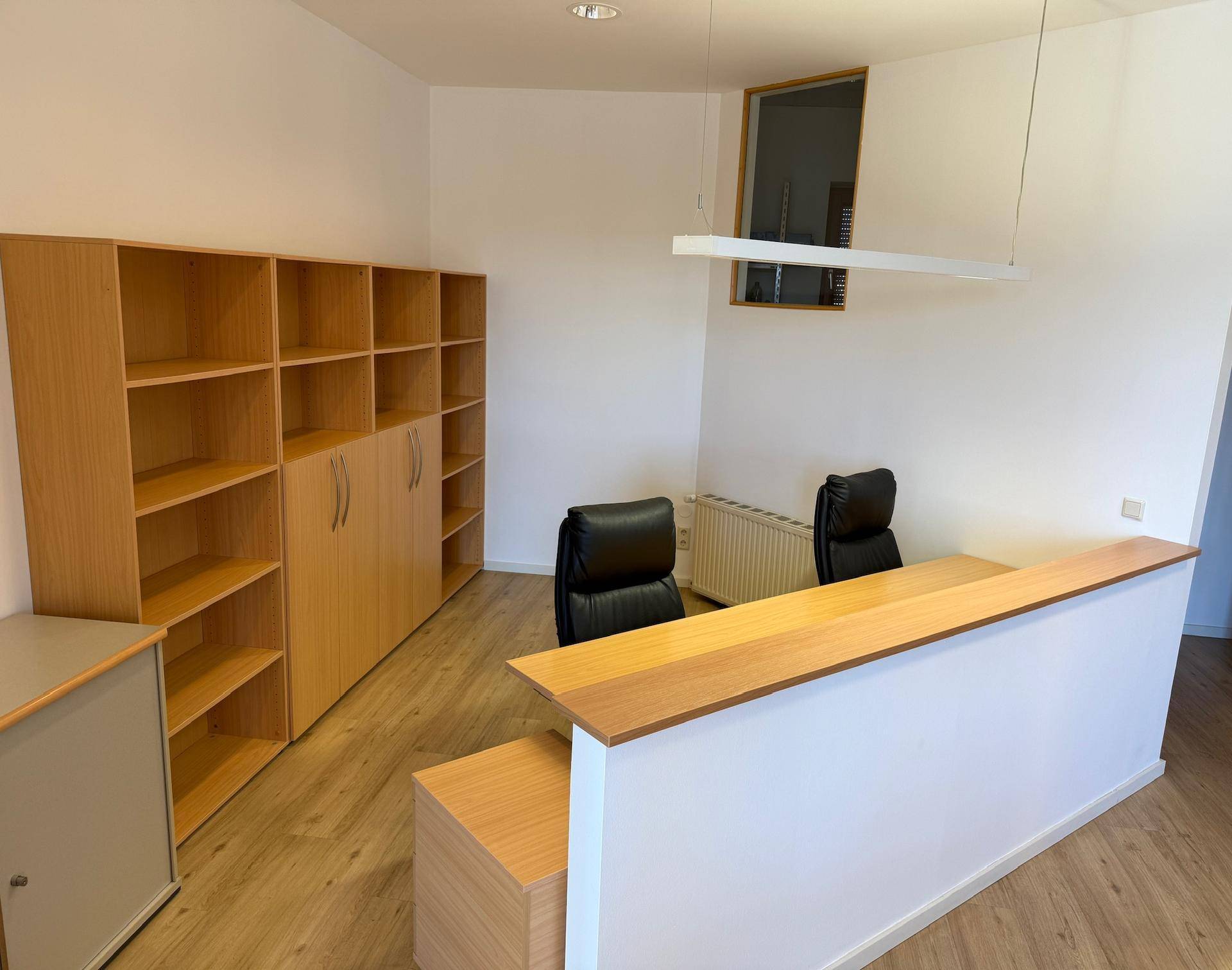 Empfangsbereich mit Theke, Bürostühlen und Holzregalen, ideal für Kundenempfang und Organisation.