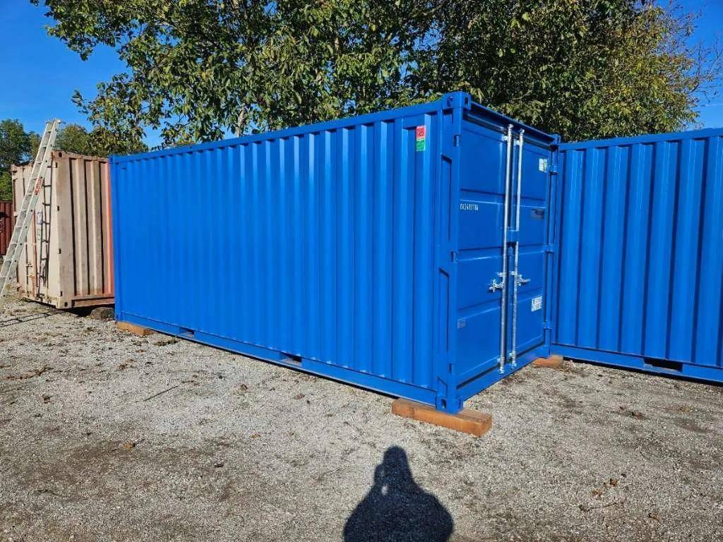 Blauer Schiffscontainer im Freien auf einem Schotterplatz, bereit für Transport oder Lagerung.
