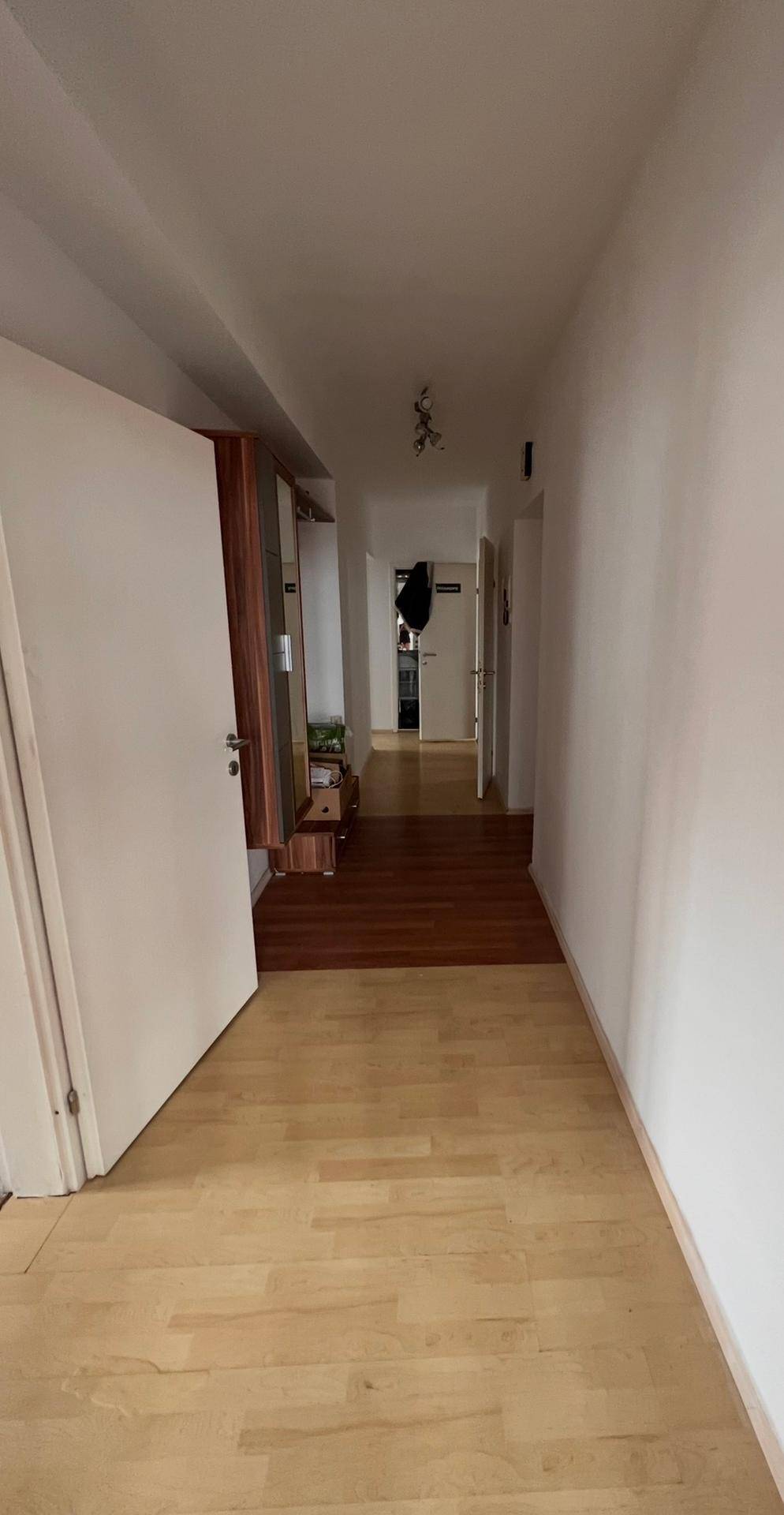 Langer Flur mit hellem Holzboden und Zugang zu verschiedenen Räumen.