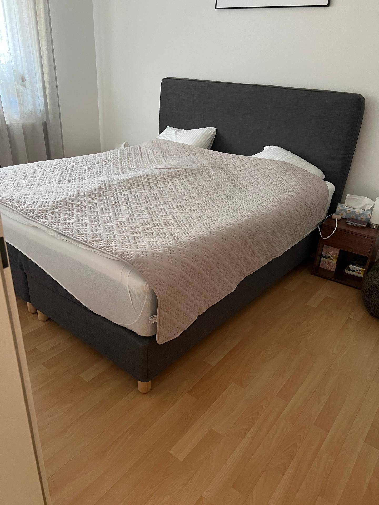 Schlafzimmer mit großem Doppelbett, Nachttisch und hellem Laminatboden.