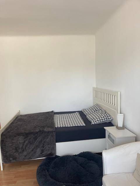 Gemütliches Schlafzimmer mit Einzelbett, Nachttisch und einem bequemen Sessel auf hellem Holzboden.