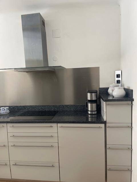 Detailansicht der Küchenzeile mit Induktionskochfeld, Dunstabzugshaube und Kaffeemaschine.