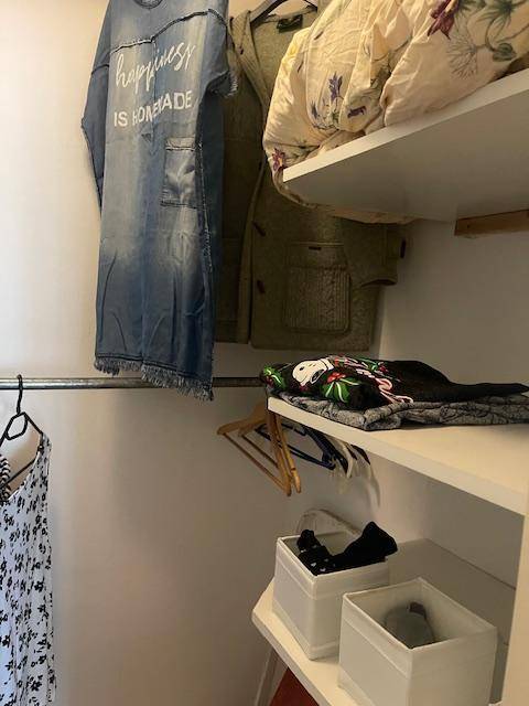 Weiterer Blick in den Abstellraum mit Kleidung auf Stangen und Regalen für zusätzlichen Stauraum.