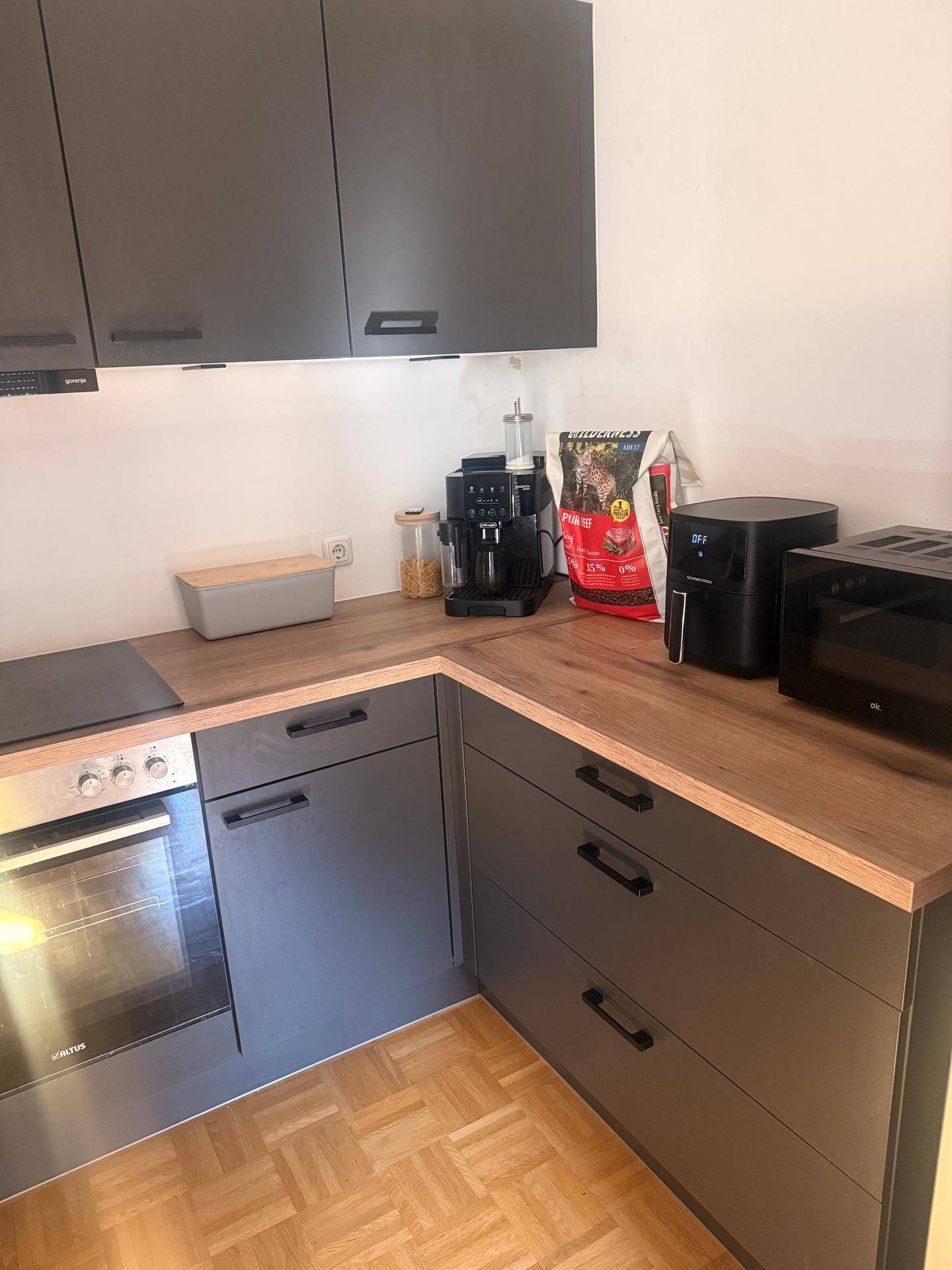 Funktionale Küche mit dunklen Unterschränken, Holz-Arbeitsplatte und modernen Küchengeräten.