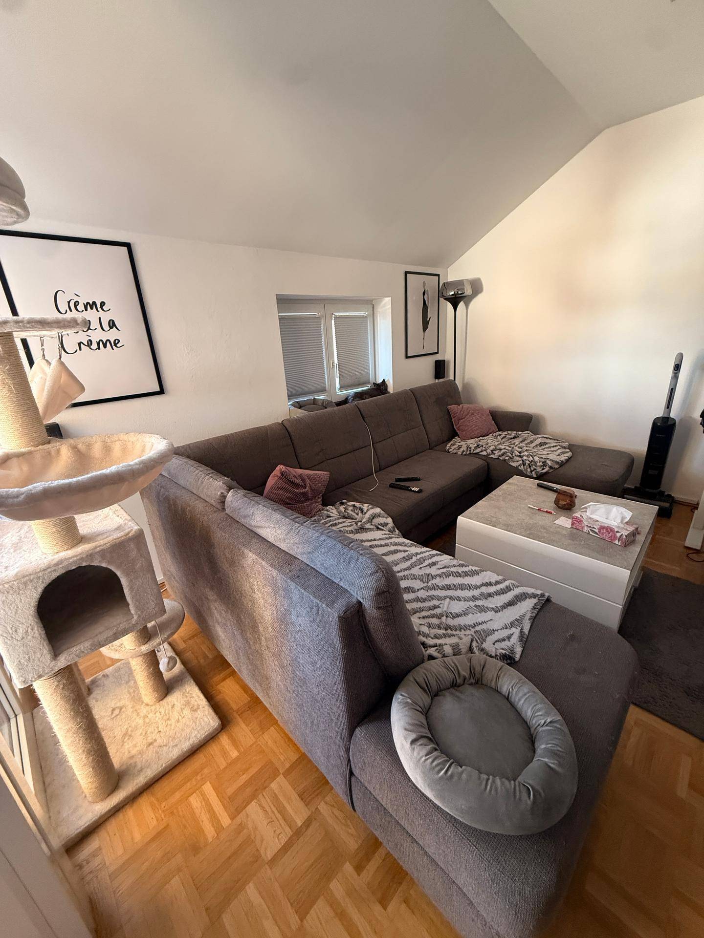 Gemütliches Wohnzimmer mit großem Ecksofa, Couchtisch und Parkettboden.