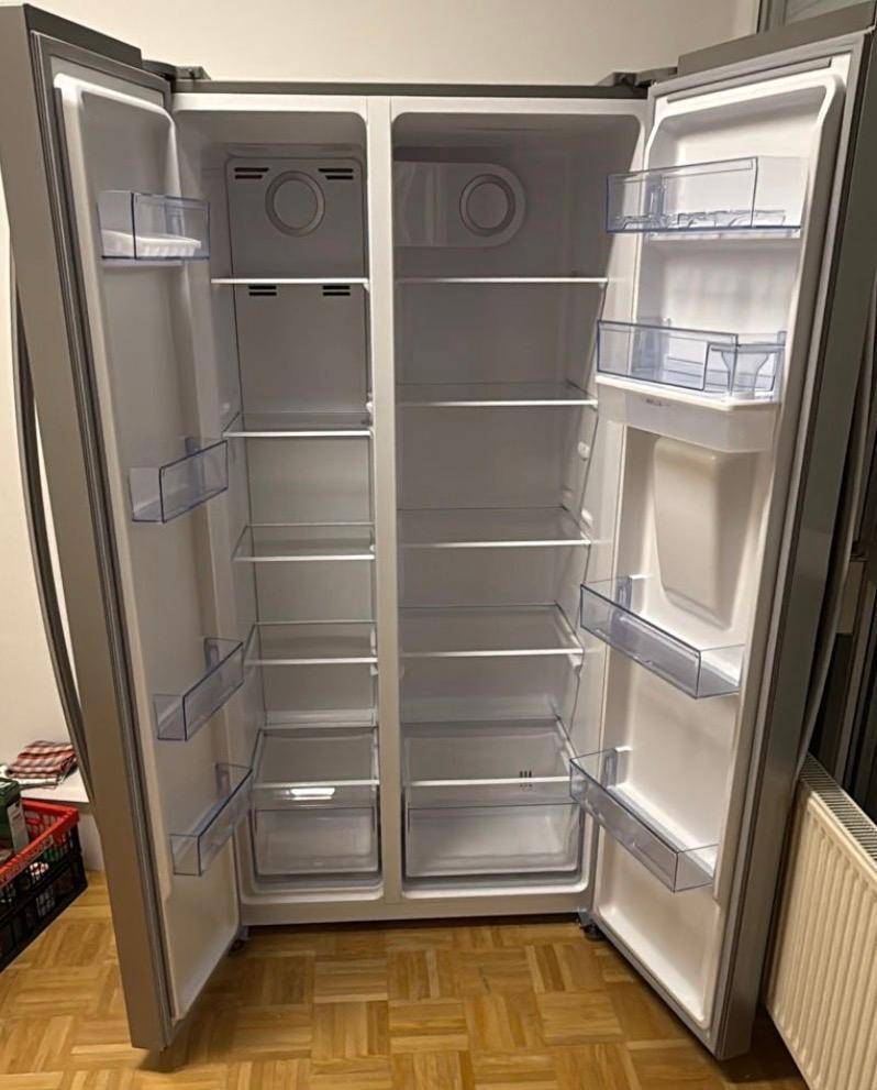 Großer, leerer Side-by-Side Kühlschrank mit Gefrierfach und vielen Ablagefächern.