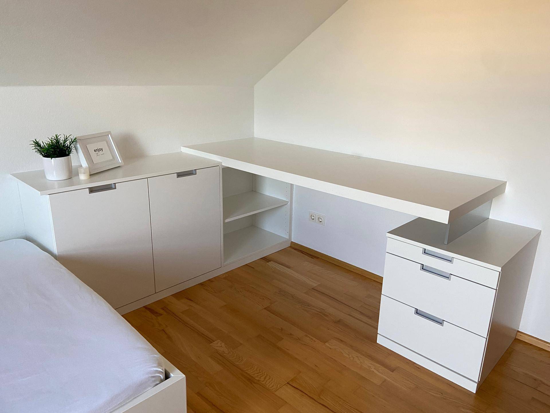 Funktionaler Arbeitsbereich im Kinderzimmer mit weißem Schreibtisch und Stauraum.
