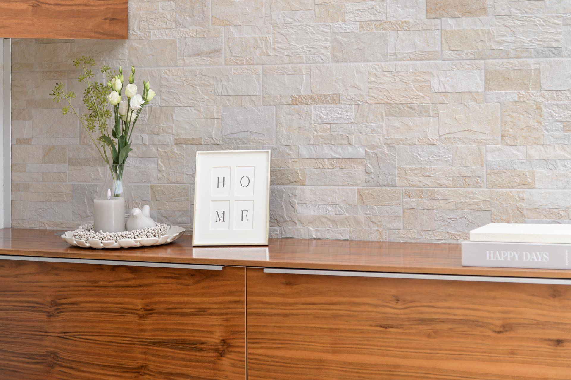 Detailansicht einer modernen Holzkommode mit Steinwandakzent und Dekoration.