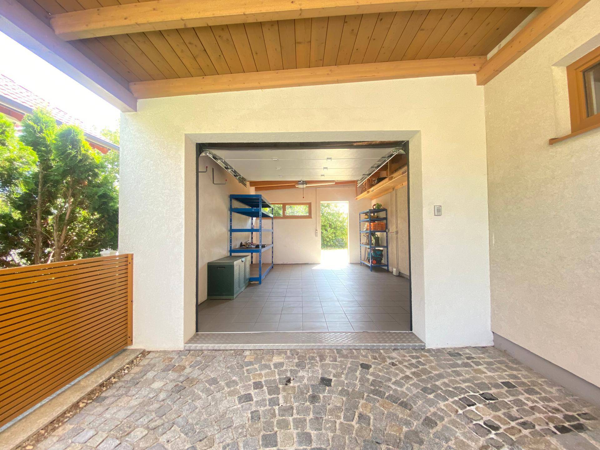 Geräumige Garage mit Fliesenboden, Regalen und direktem Zugang zum Außenbereich.