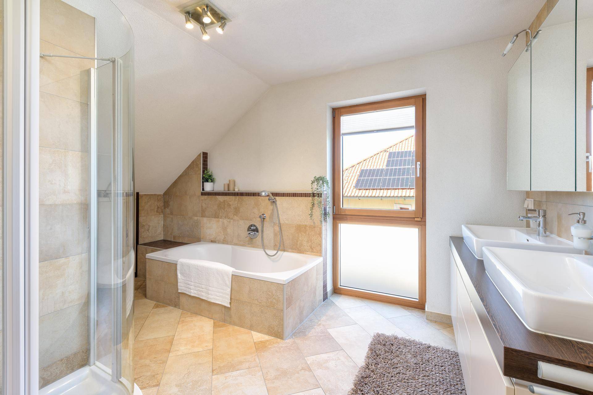 Modernes Badezimmer im Dachgeschoss mit Badewanne, Dusche und Doppelwaschbecken.